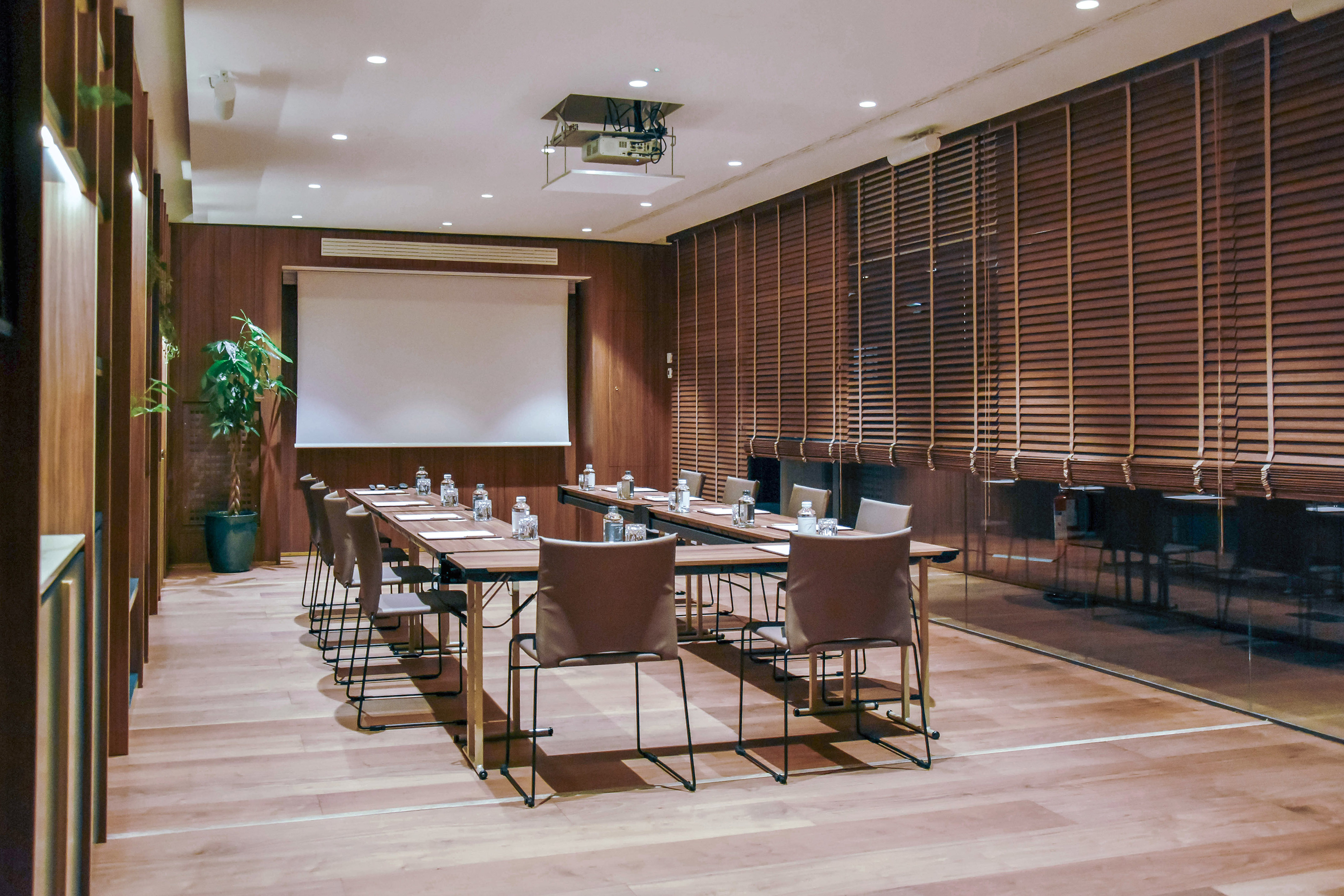 Modern conference room with projector, long table, chairs, wood interior.