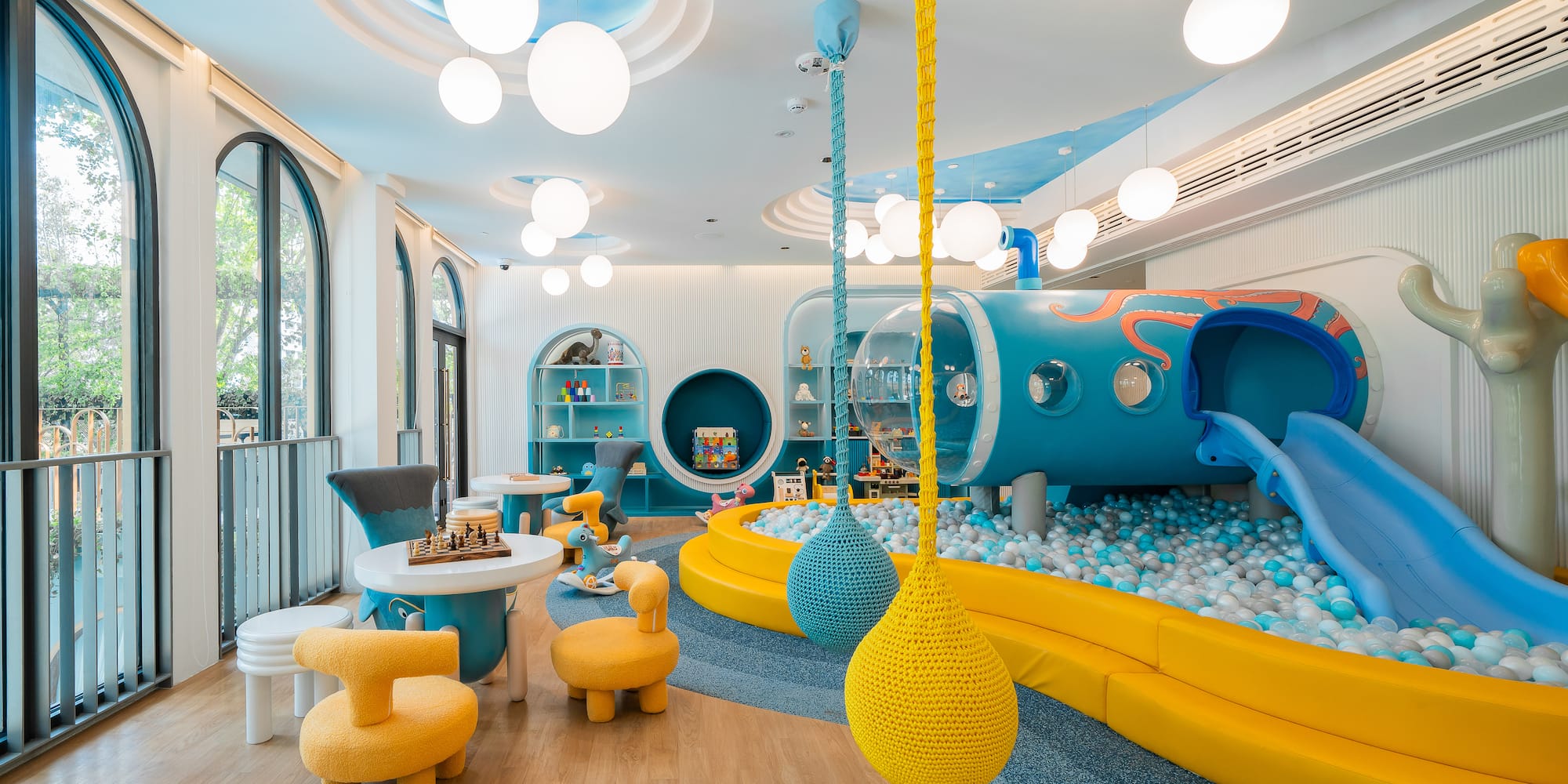 a room with a play area and a play area with a slide and balls
