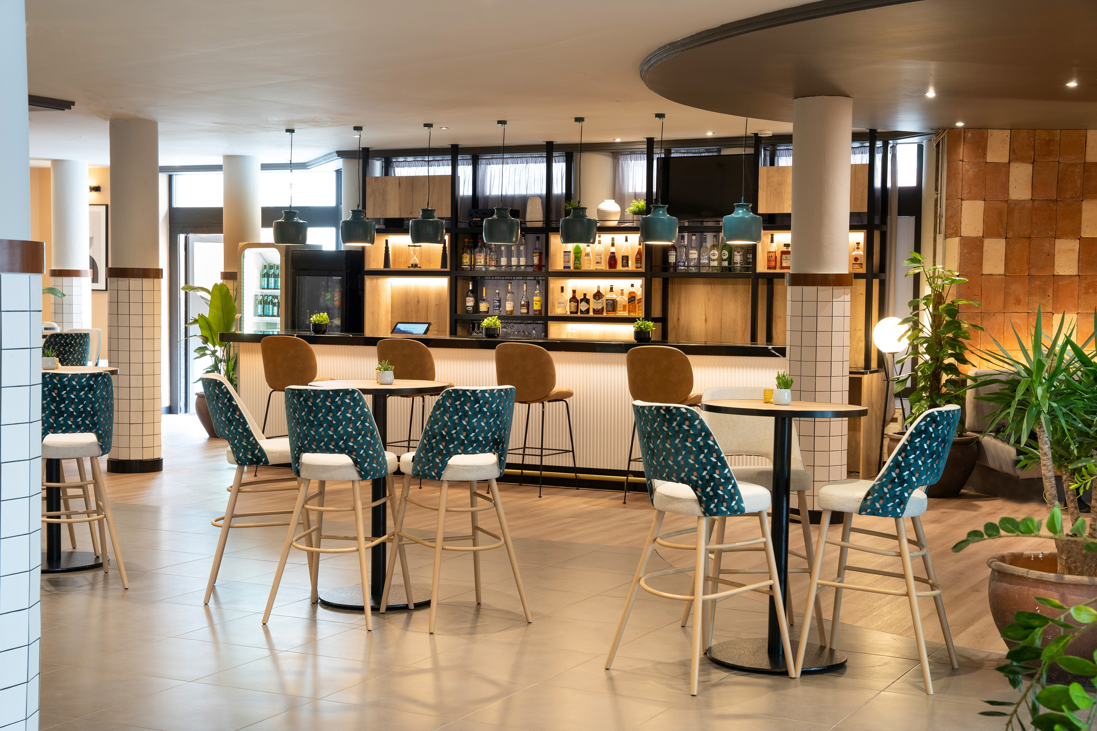 Modern hotel bar with liquor display, patterned stools, and tables.