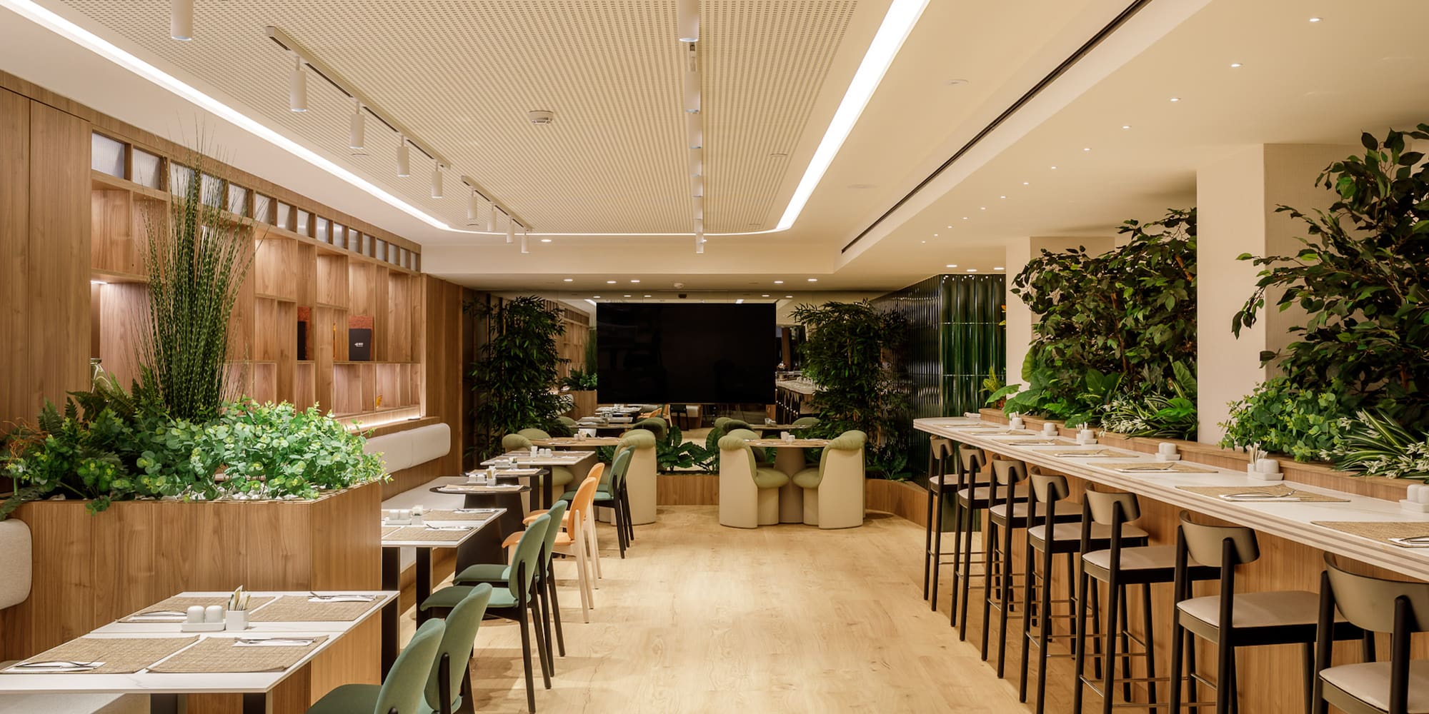 Modern restaurant with wooden walls, lush plants, and diverse dining seating.