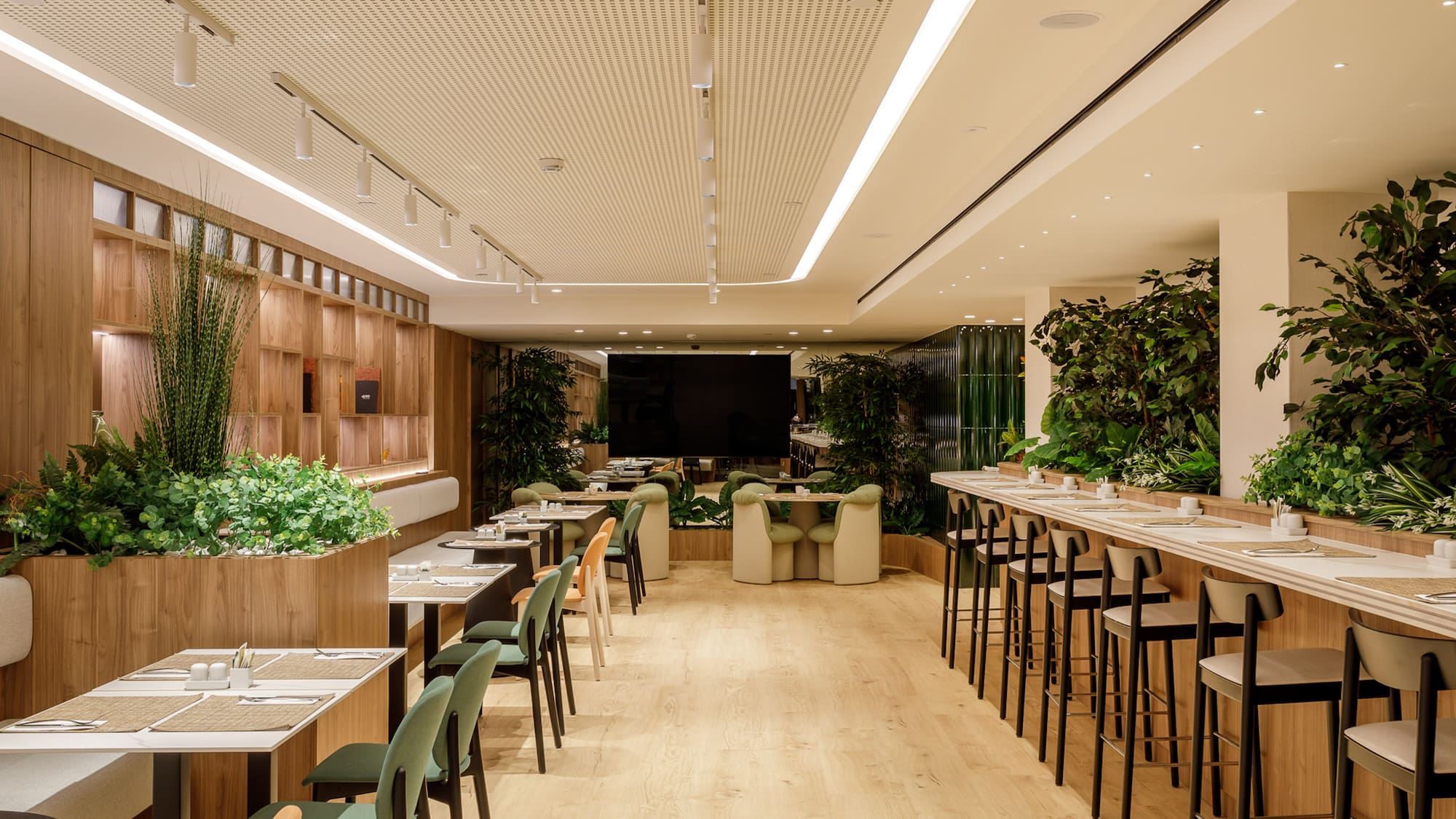 Modern restaurant with wooden walls, lush plants, and diverse dining seating.