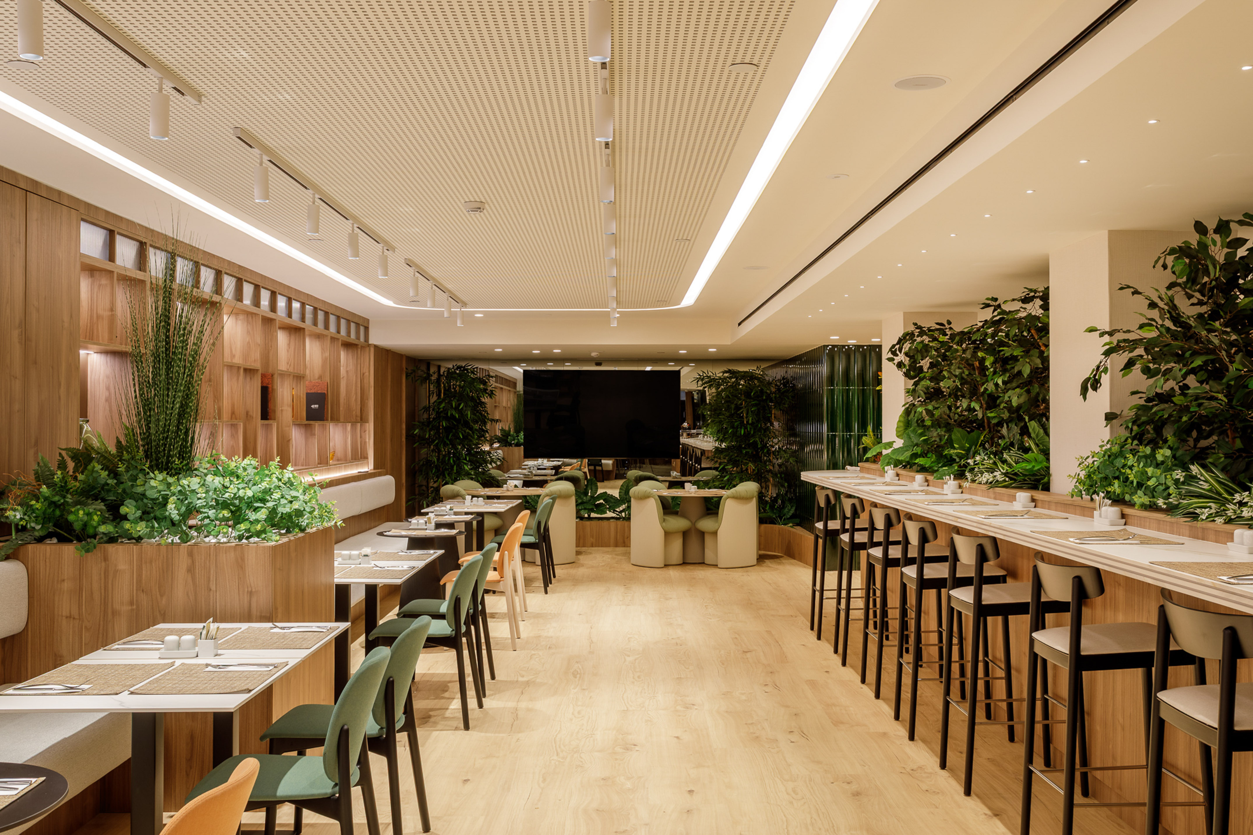 Modern restaurant with wooden walls, lush plants, and diverse dining seating.