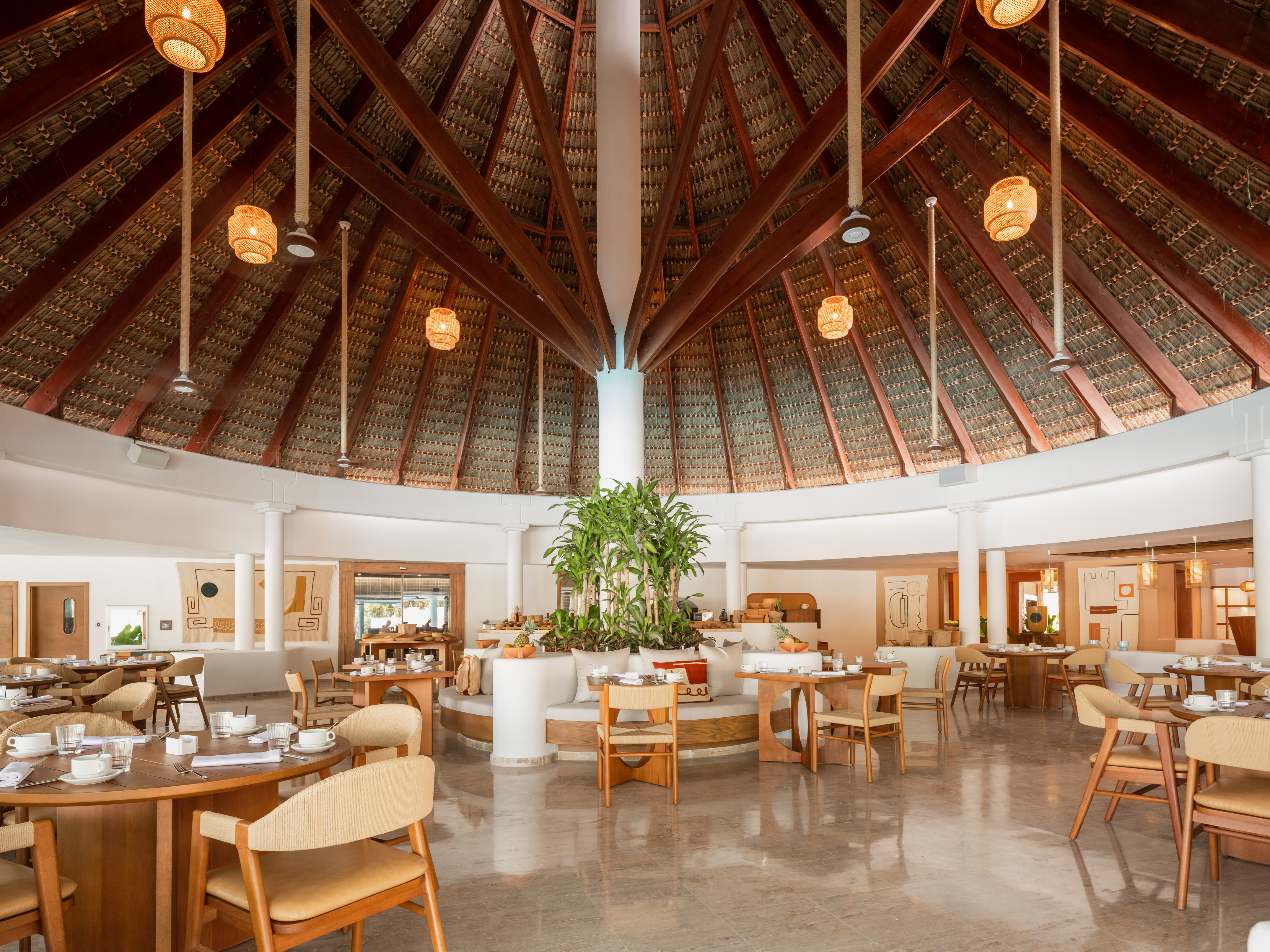 Spacious tropical restaurant with thatched roof, wooden tables, and rattan lamps.