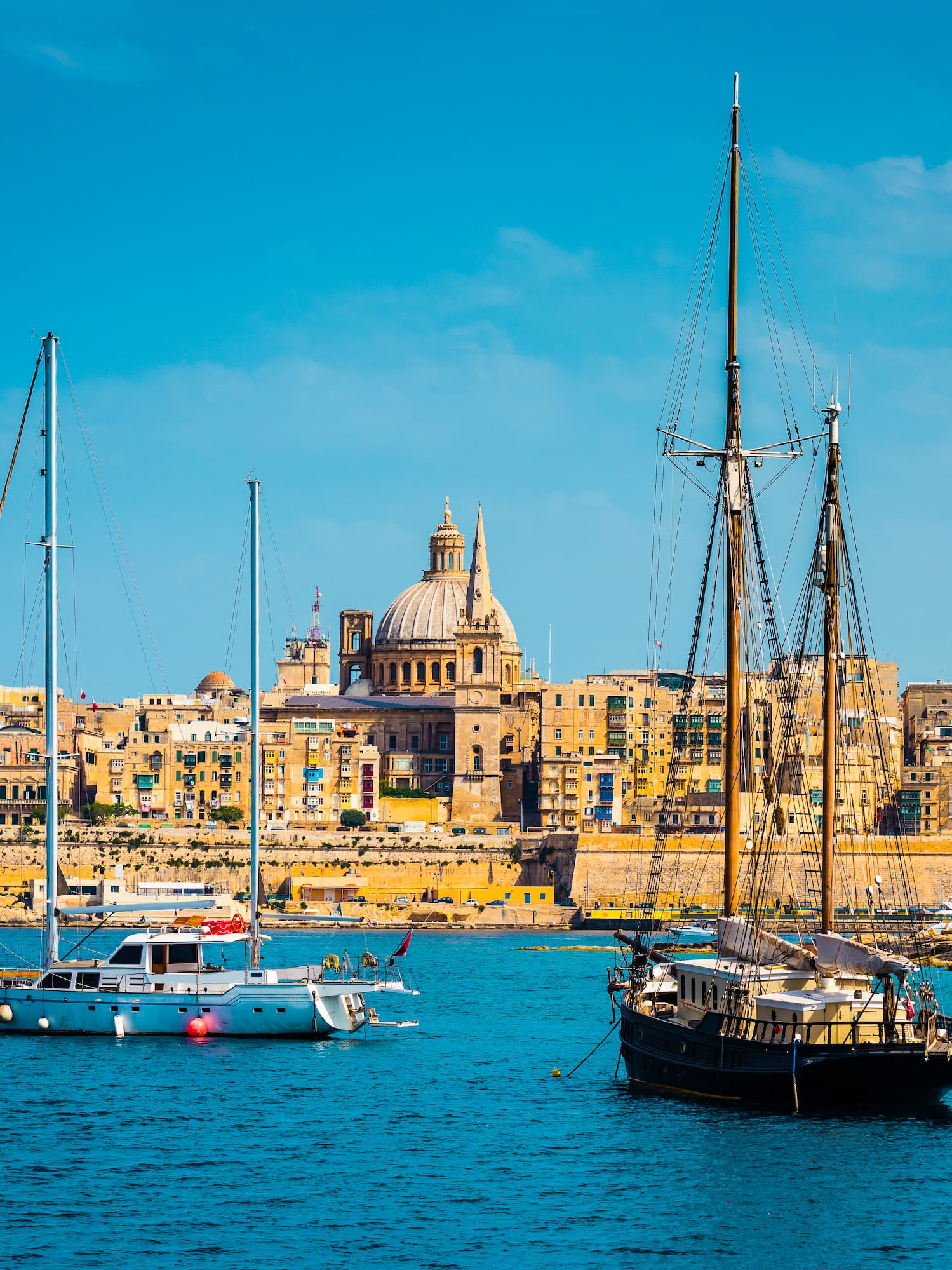 Valletta, Malta: historic city skyline, St. Paul's dome, and yachts in harbor.