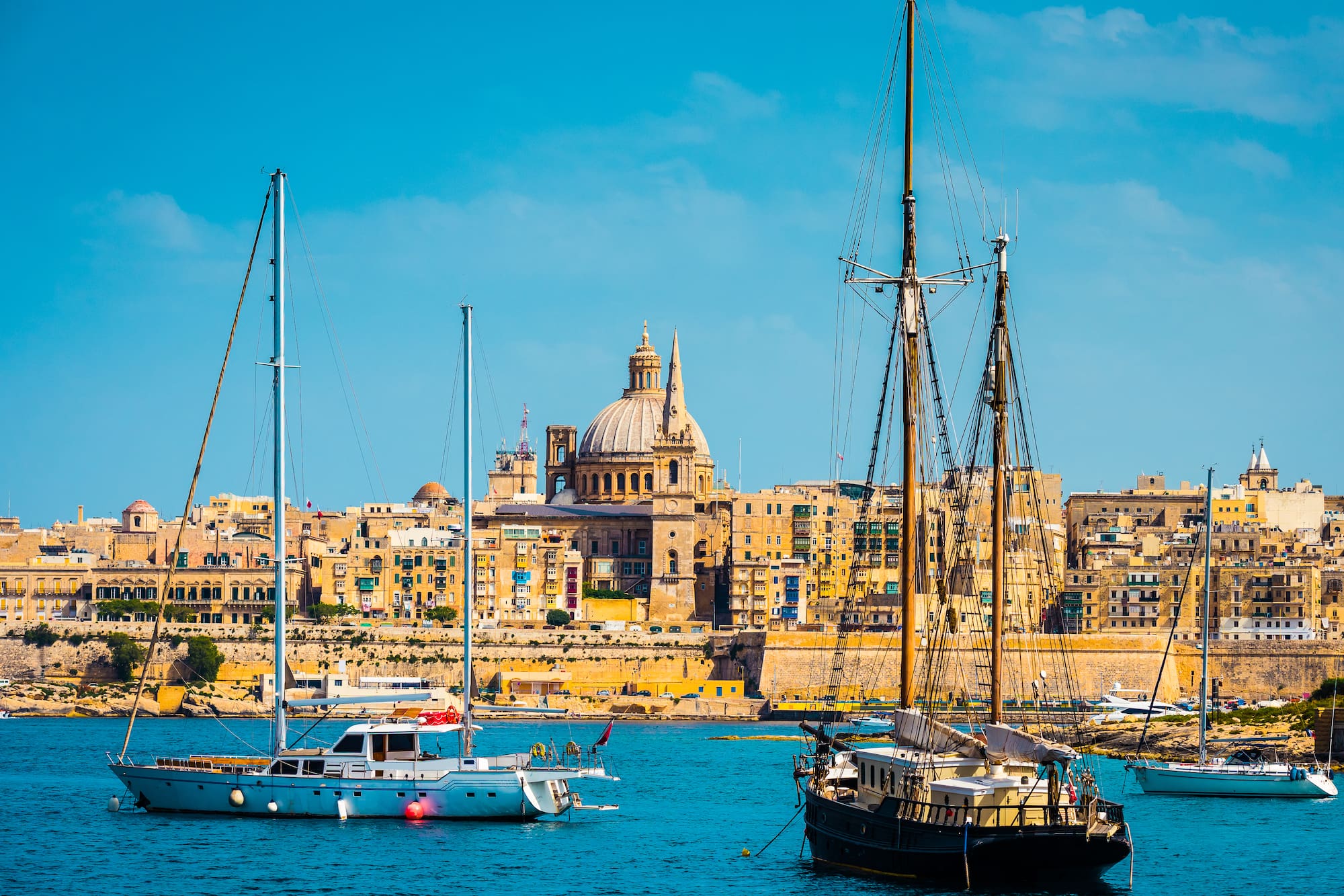 Valletta, Malta: historic city skyline, St. Paul's dome, and yachts in harbor.