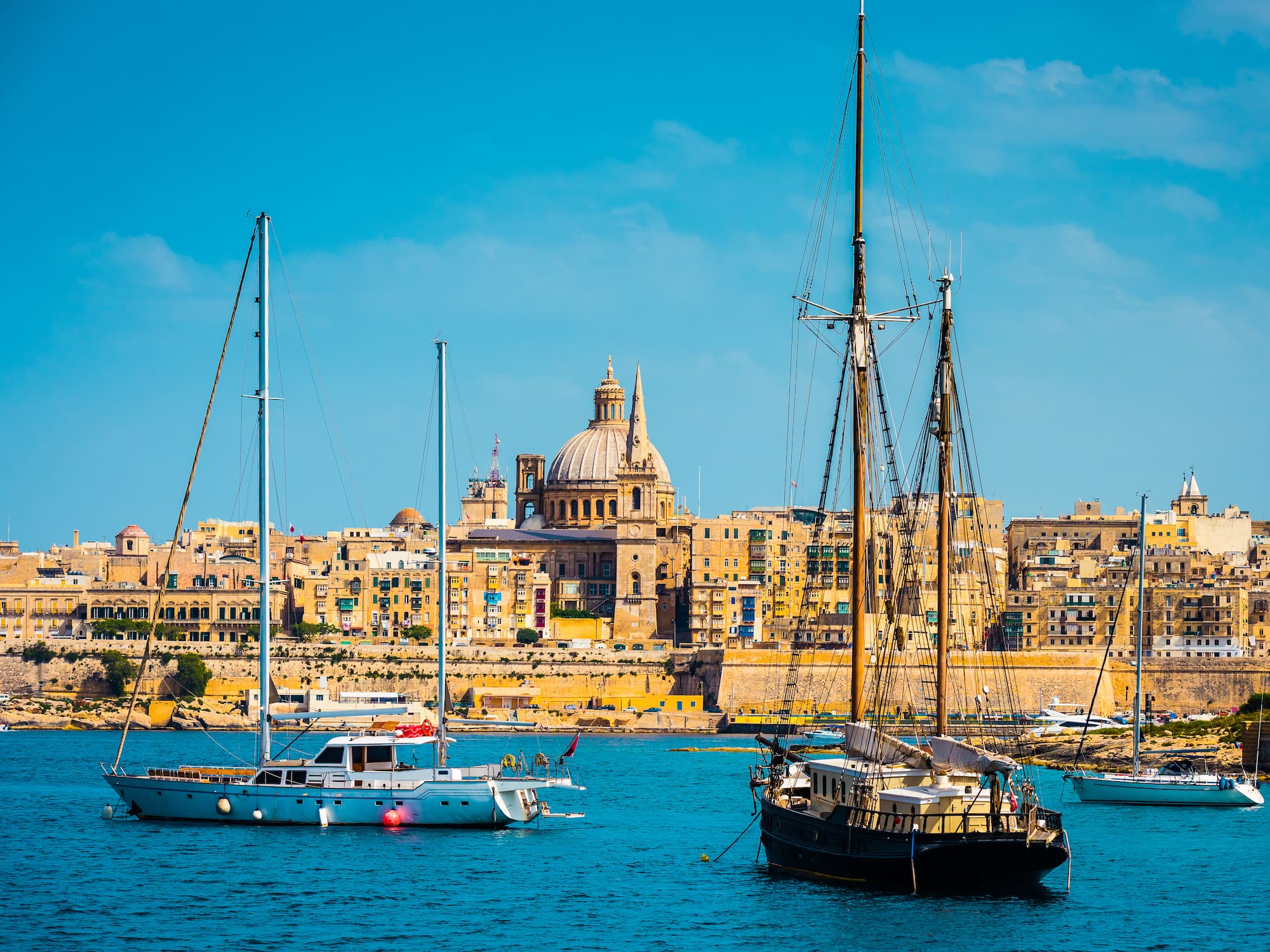 Valletta, Malta: historic city skyline, St. Paul's dome, and yachts in harbor.