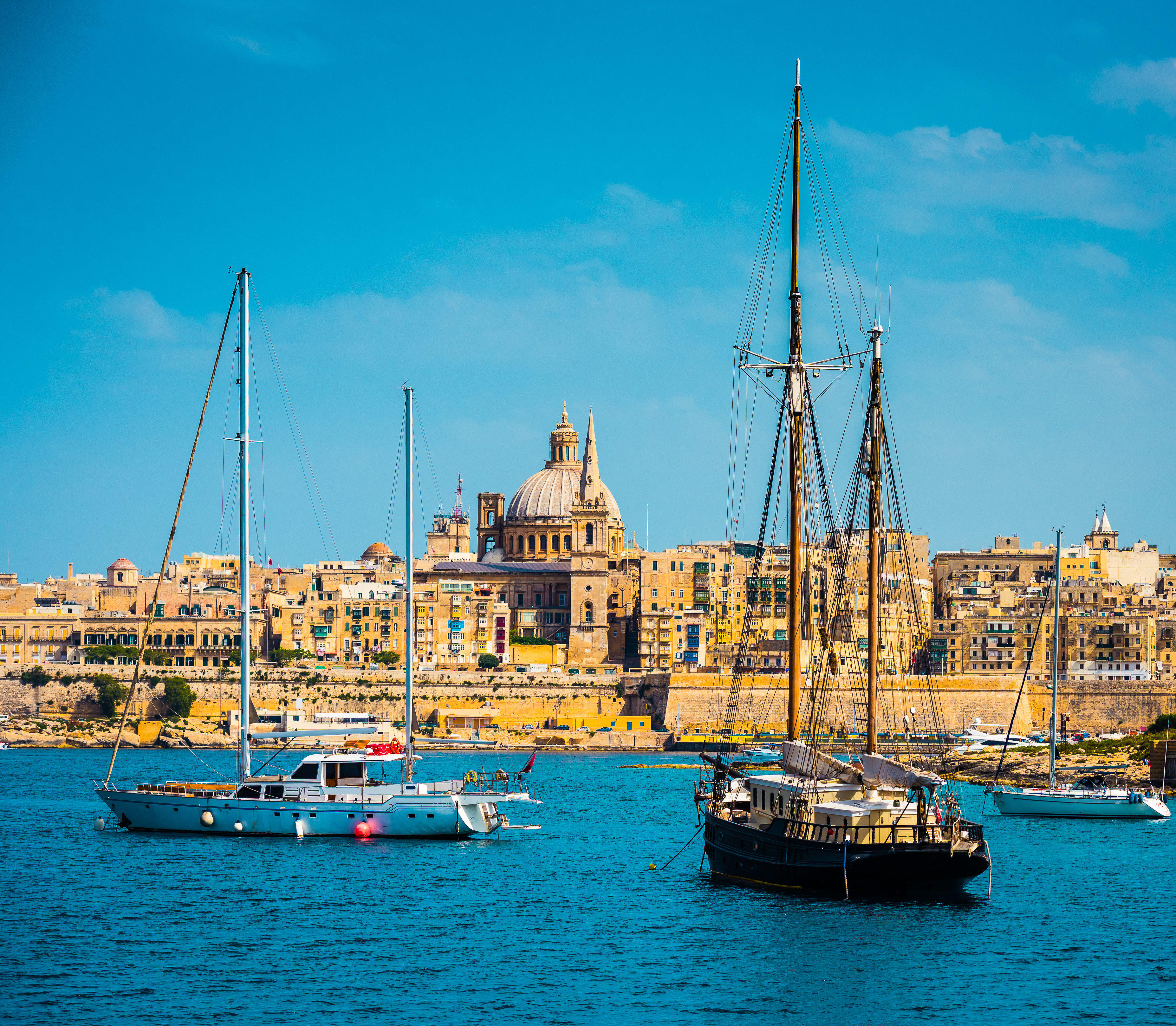 Valletta, Malta: historic city skyline, St. Paul's dome, and yachts in harbor.