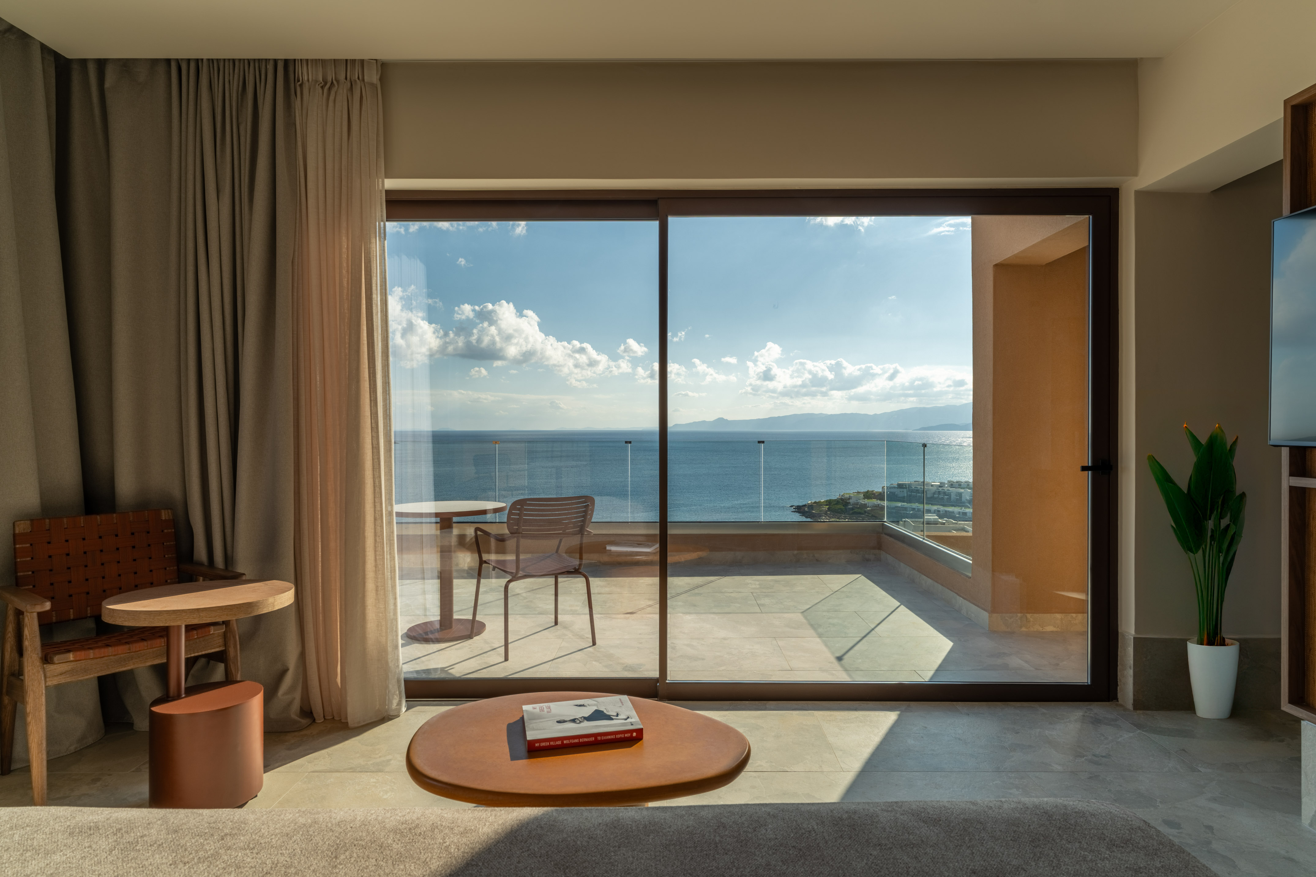Modern room with ocean view balcony, glass doors, and contemporary furnishings.
