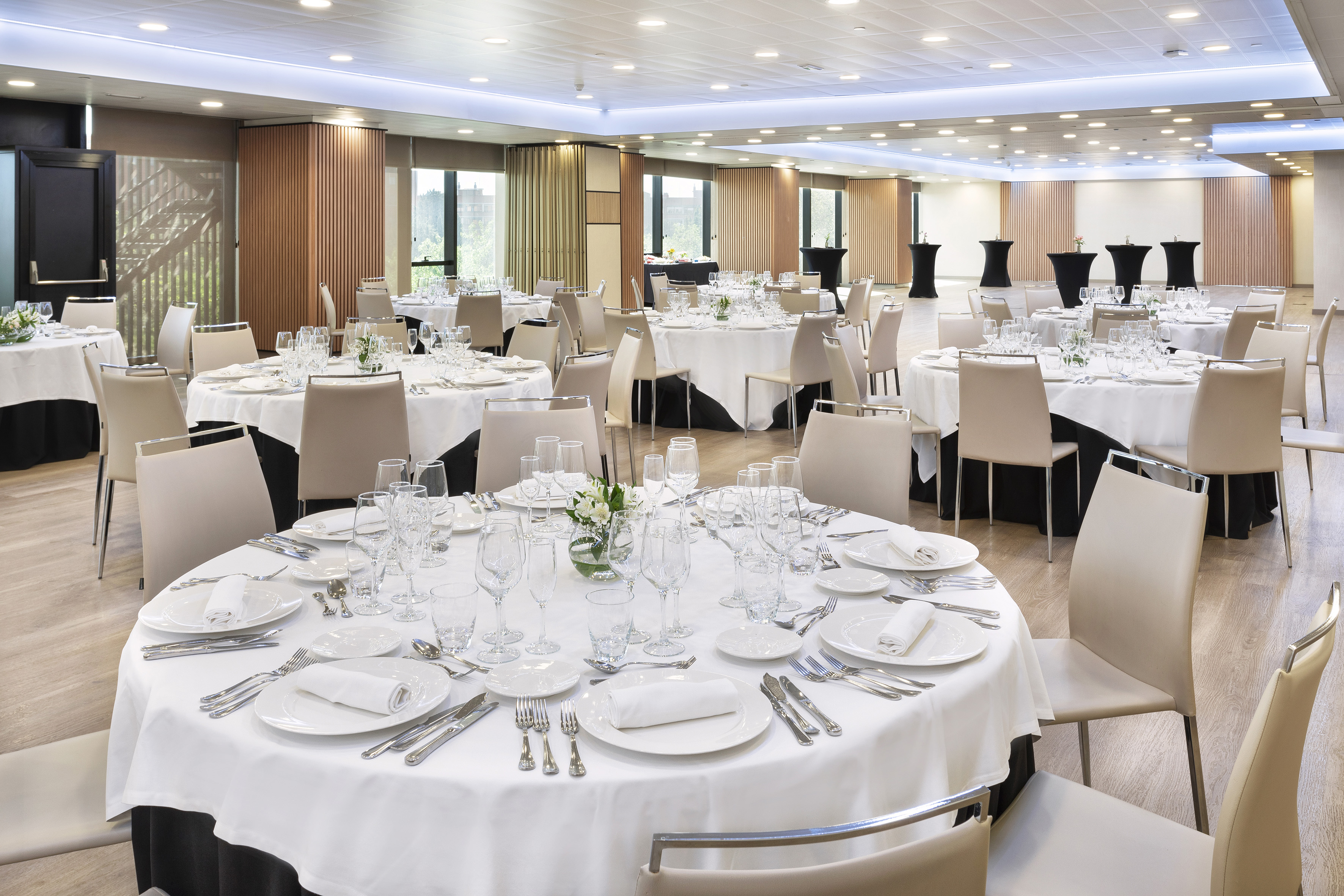 Elegant hotel ballroom set for an event with round dining tables and chairs.