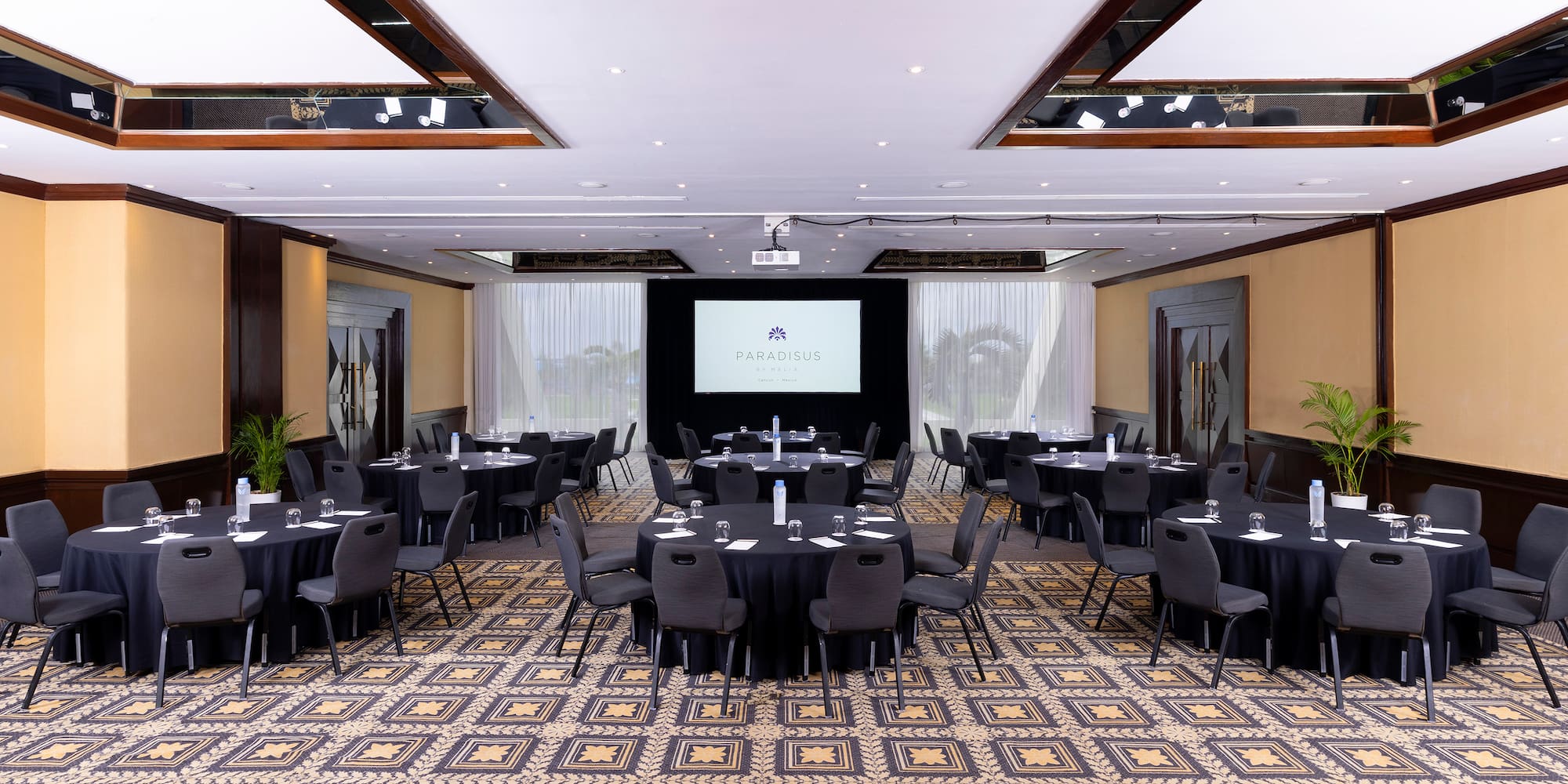 a room with a large screen and tables