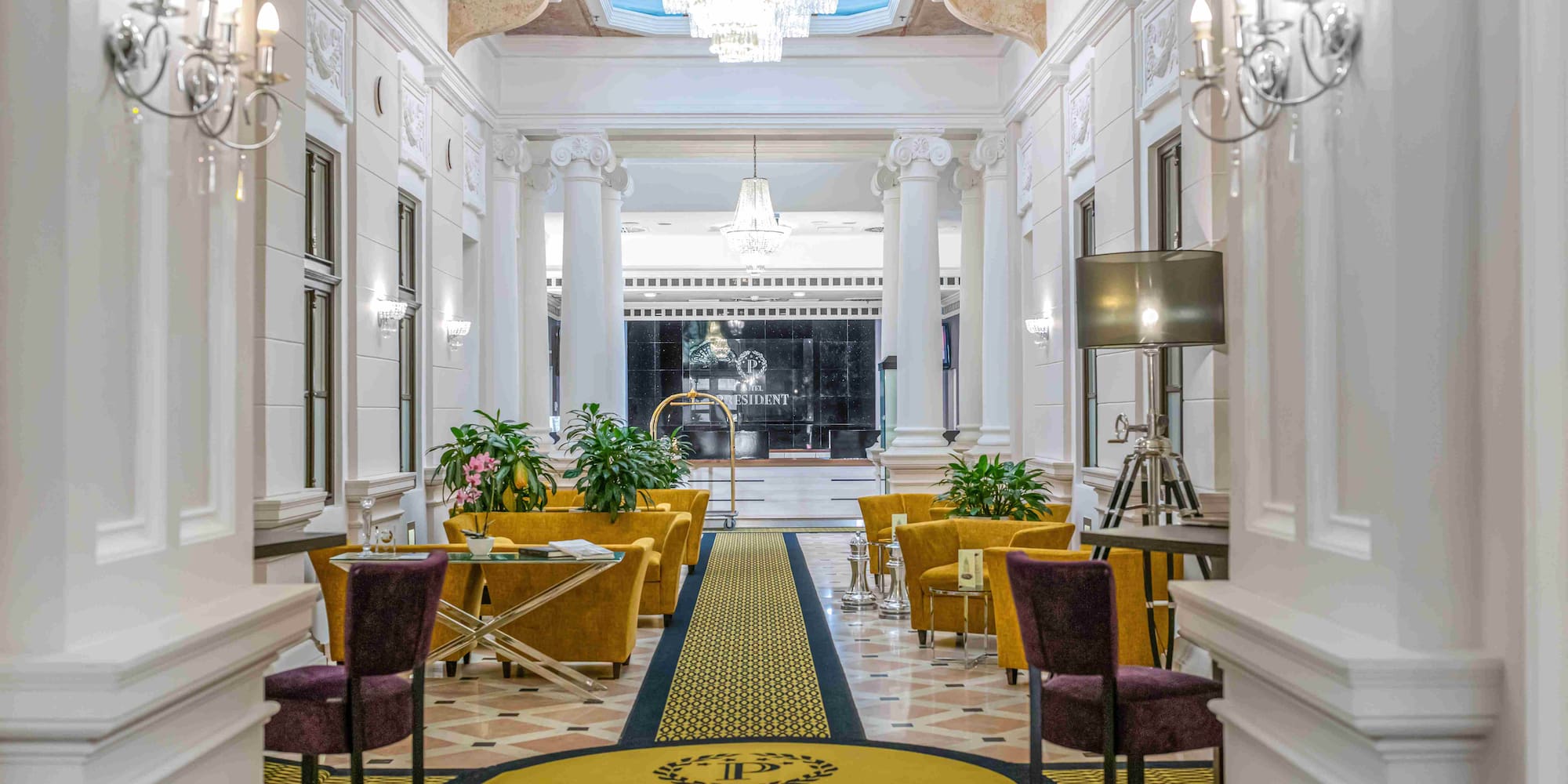 Hotel President Budapest luxurious lobby, chandeliers, yellow armchairs, reception.