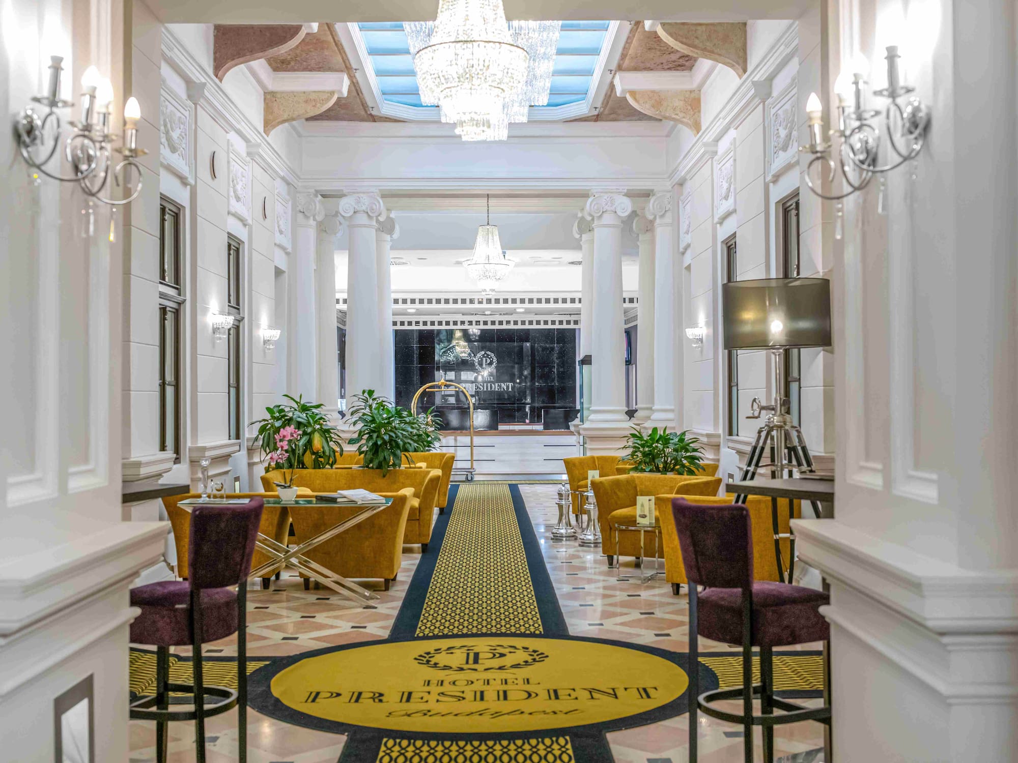 Hotel President Budapest luxurious lobby, chandeliers, yellow armchairs, reception.