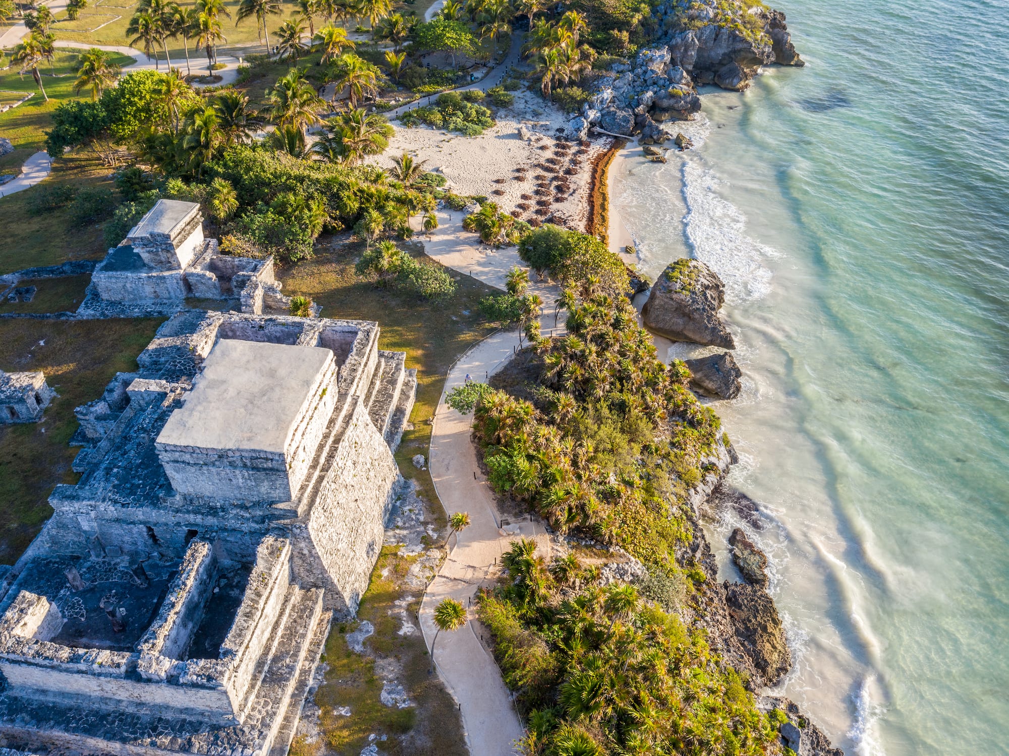 Aerial view of Tulum Mayan ruins, tropical beach, and turquoise ocean.