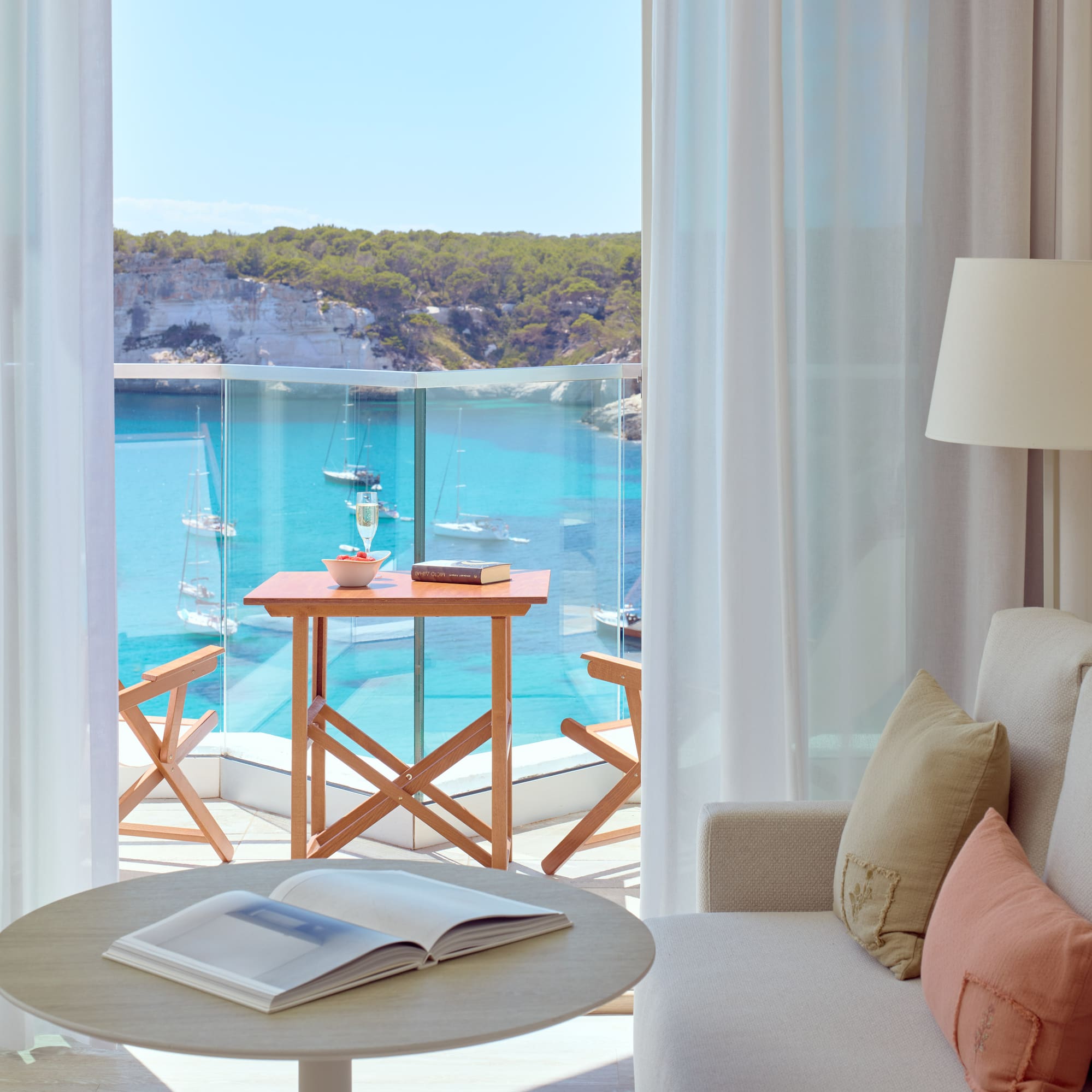 a room with a view of the ocean and a table and chairs
