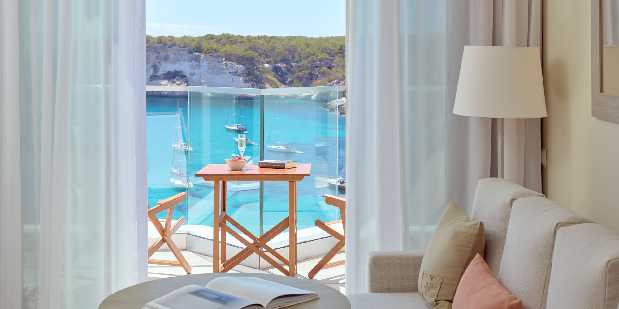 a room with a view of the ocean and a table and chairs