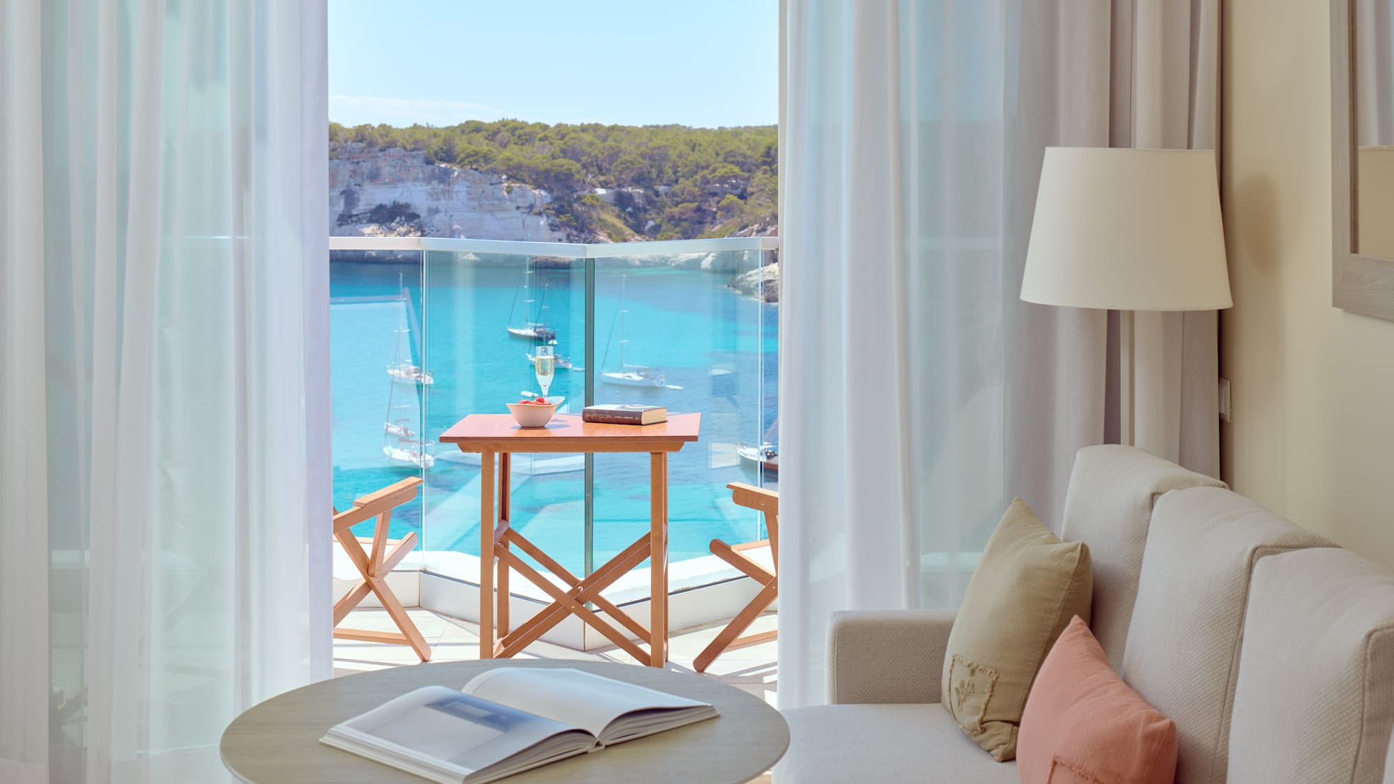 a room with a view of the ocean and a table and chairs