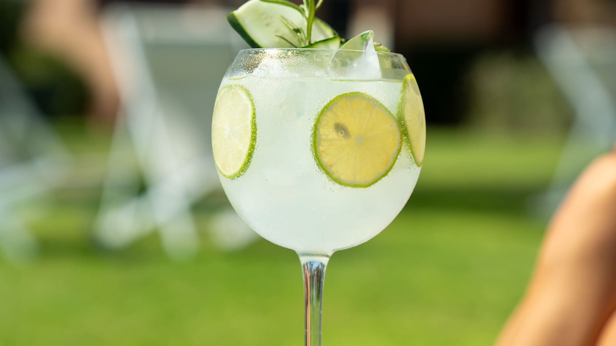 a glass of water with limes and ice on a table