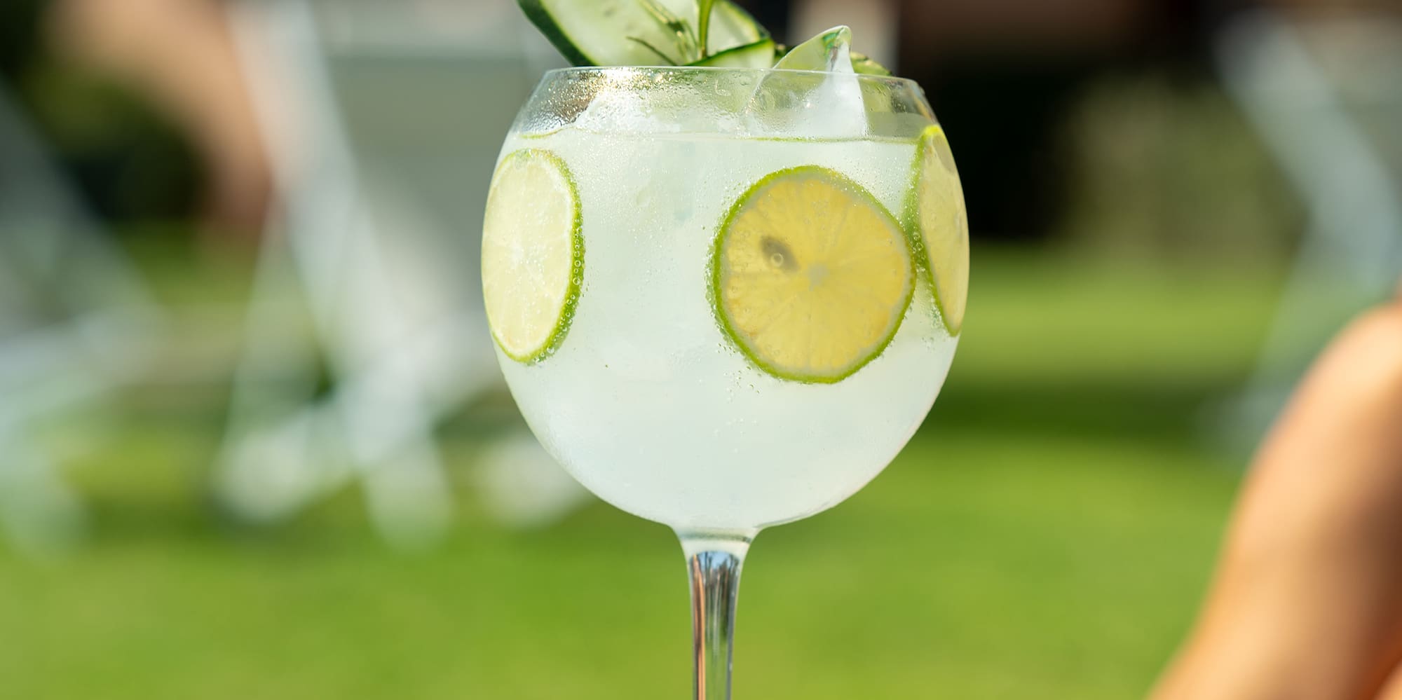 a glass of water with limes and ice on a table