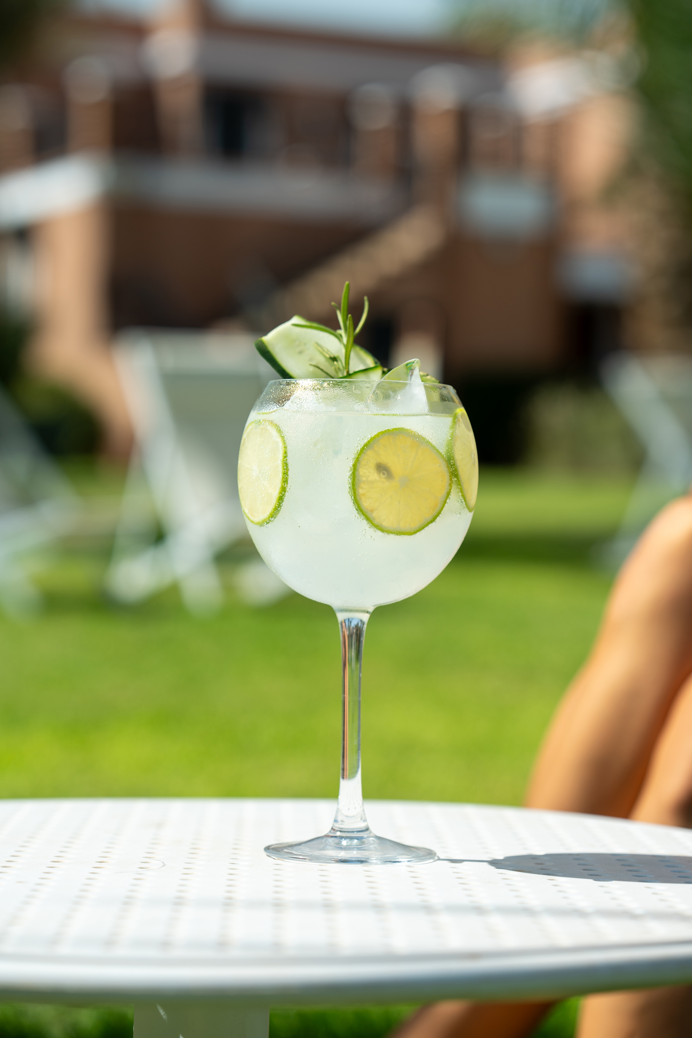 Refreshing summer cocktail with lime, cucumber, and rosemary on an outdoor table.