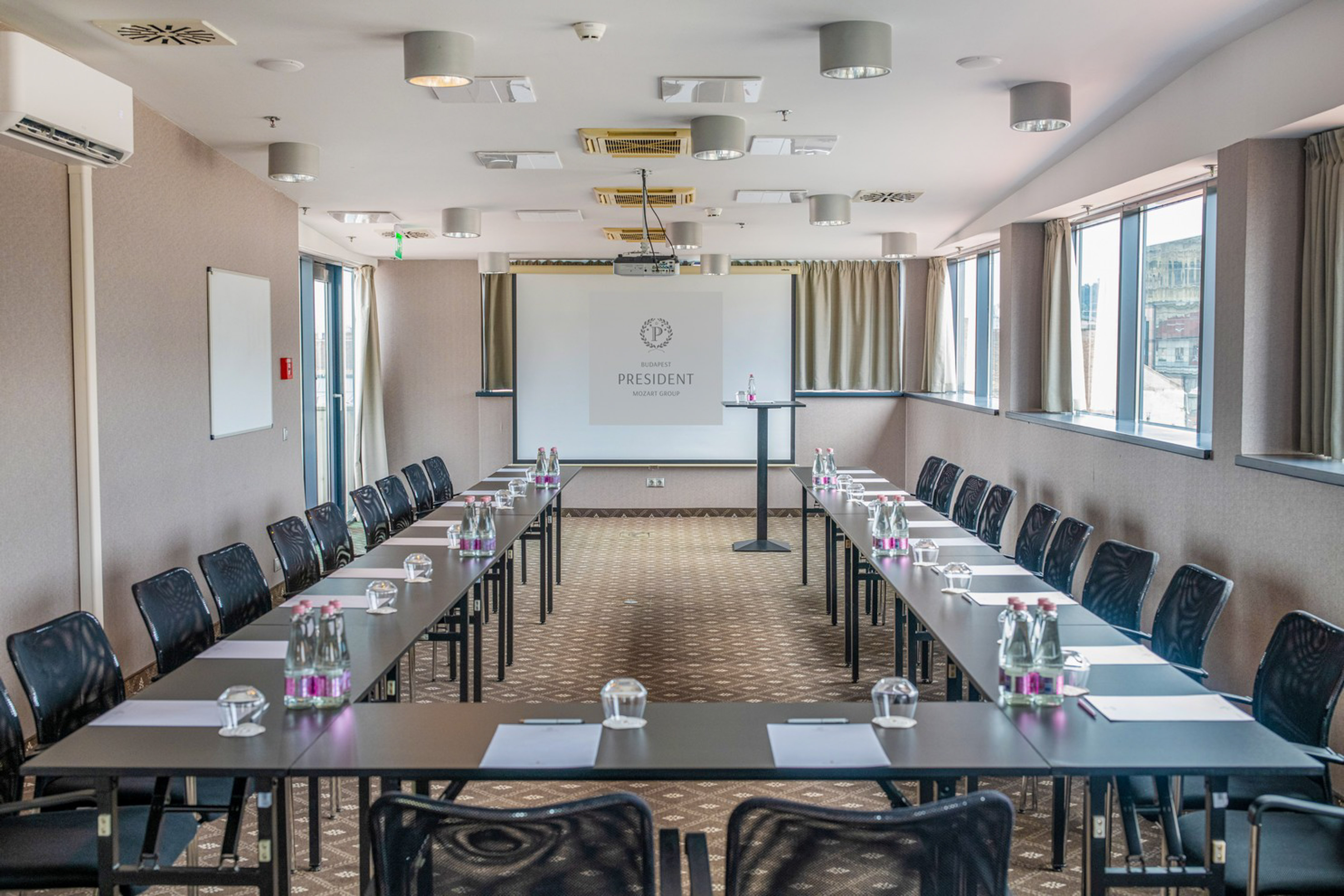 U-shape conference room at Budapest President Hotel with projector and tables.
