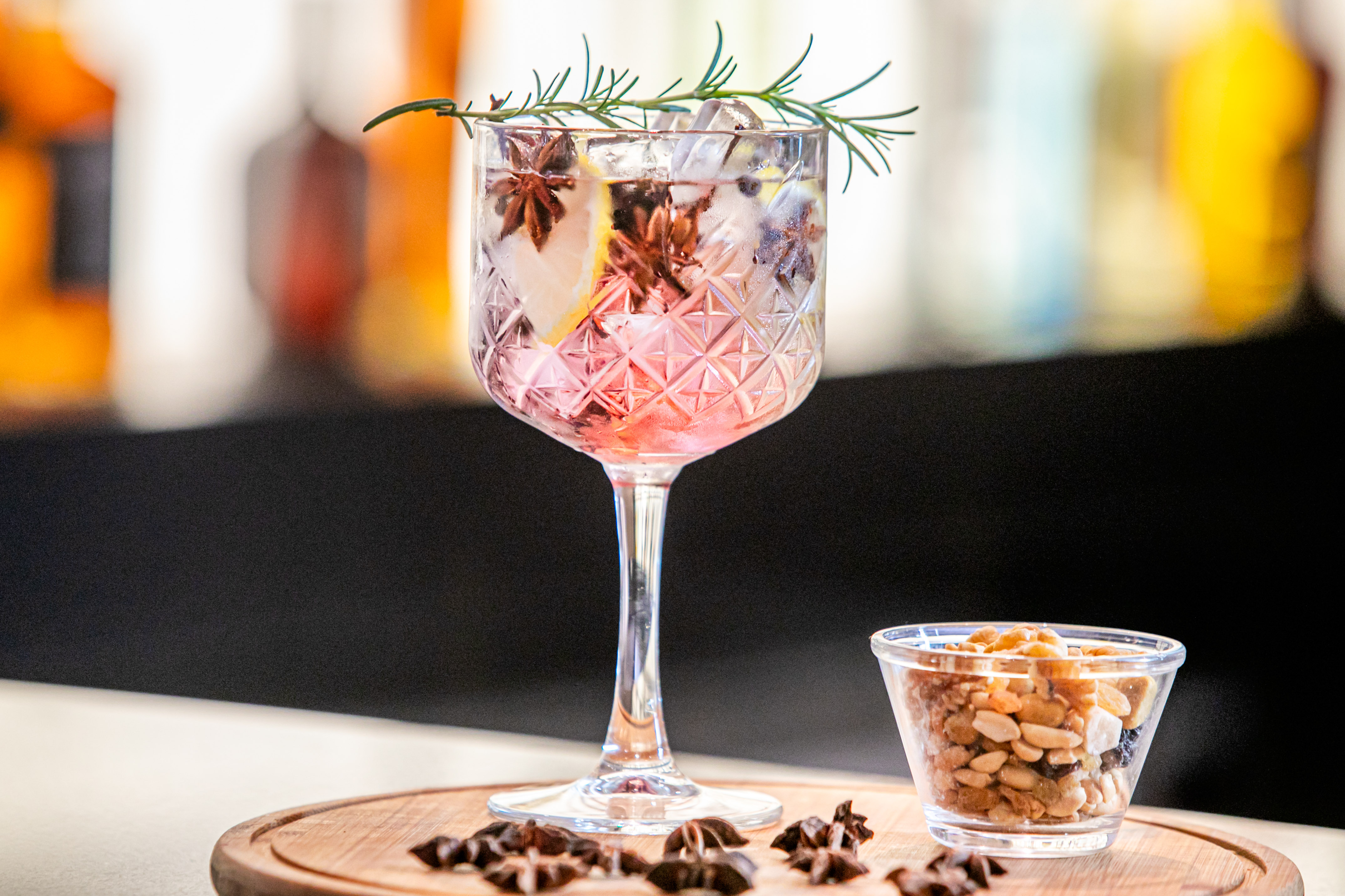 a glass of pink drink with ice and rosemary in it