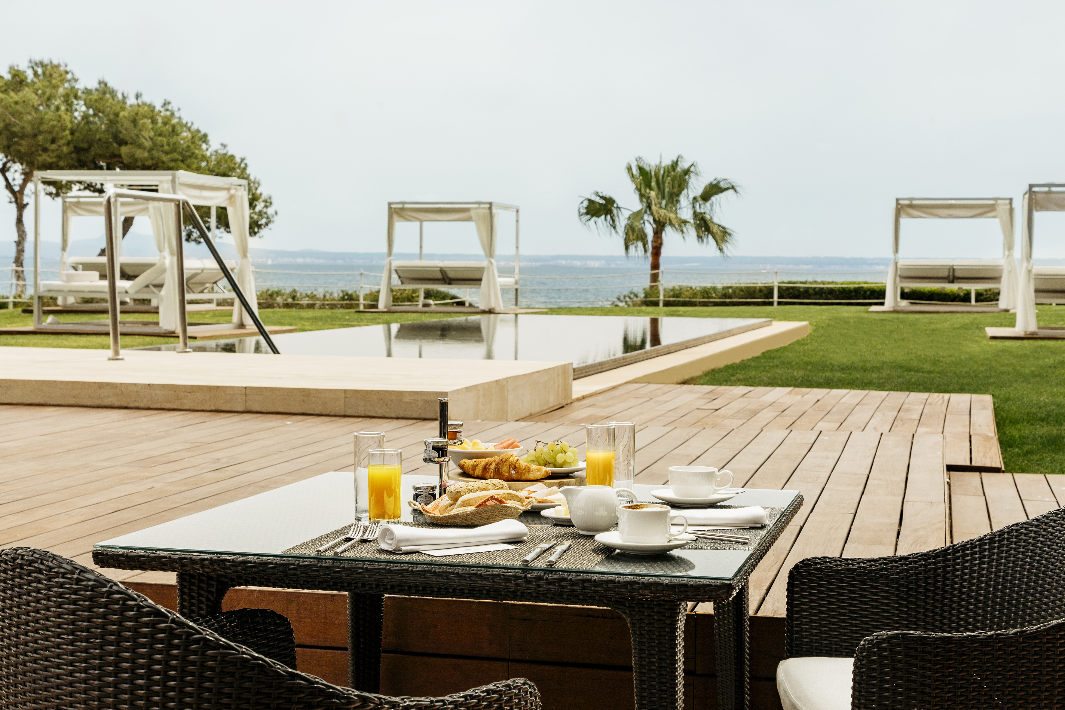 Outdoor breakfast on a patio with ocean view, infinity pool, and luxury cabanas.