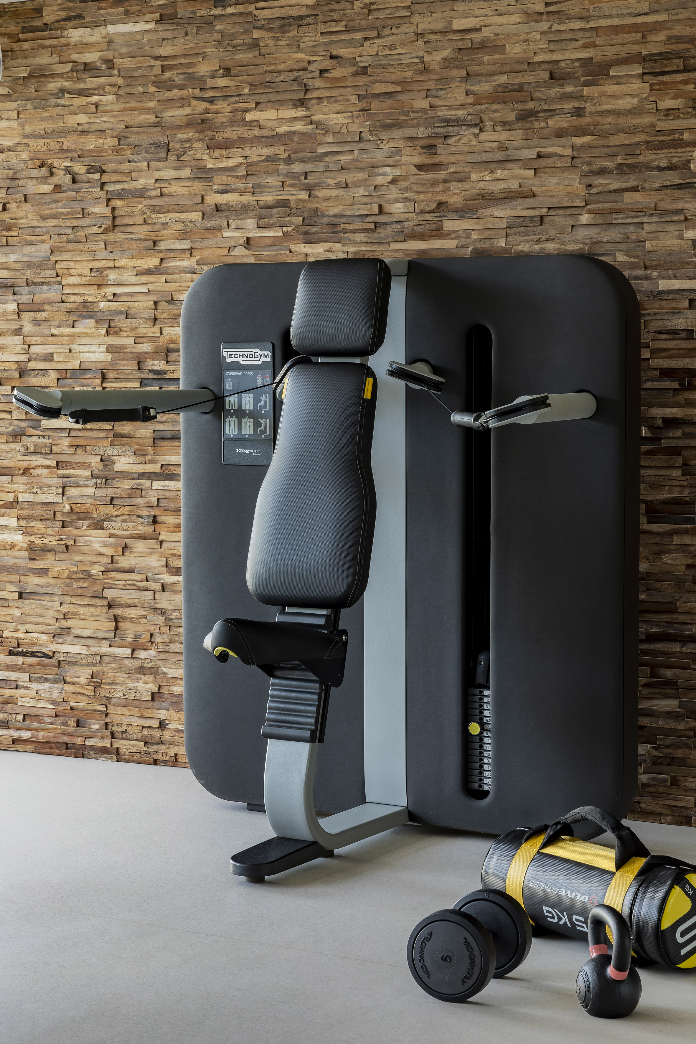 Technogym Overhead Press machine and fitness gear in a stylish home gym.