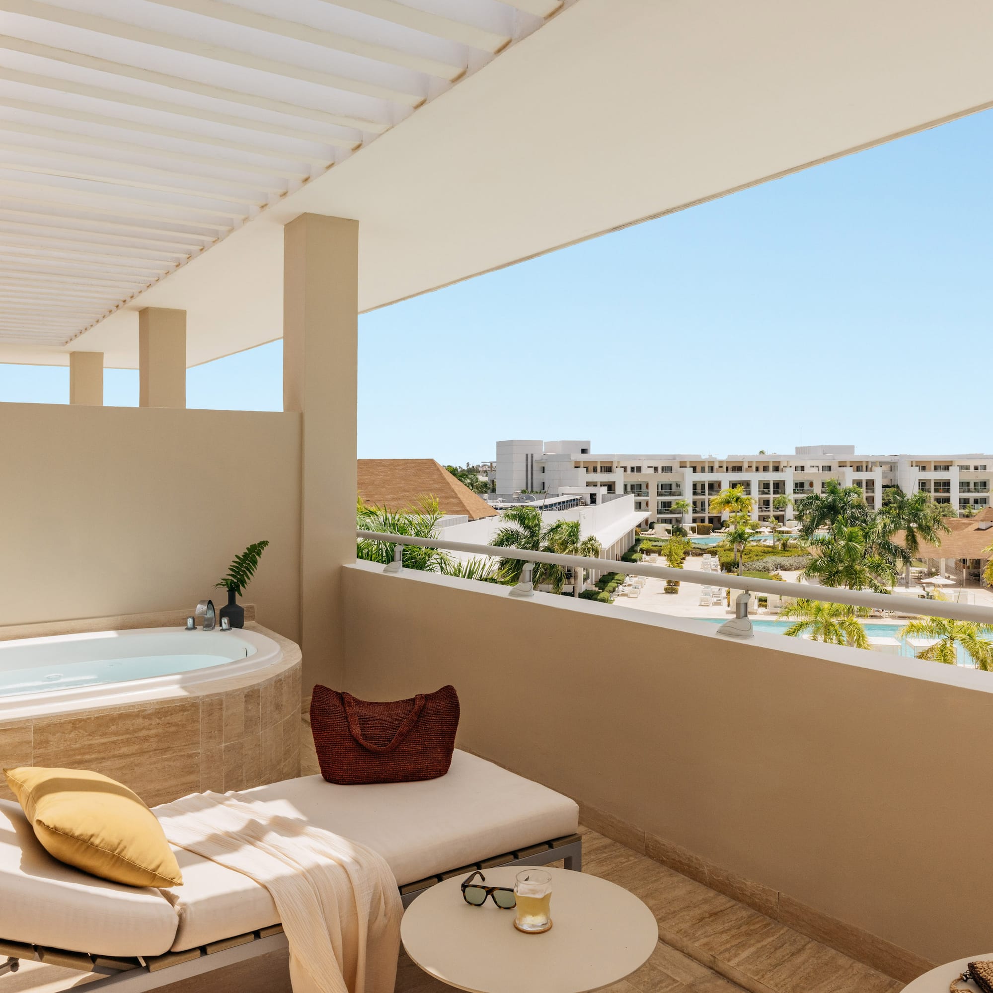 Luxury resort balcony with jacuzzi, lounge, and pool view.