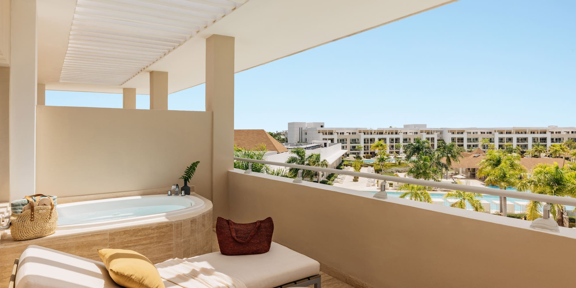 Luxury resort balcony with jacuzzi, lounge, and pool view.