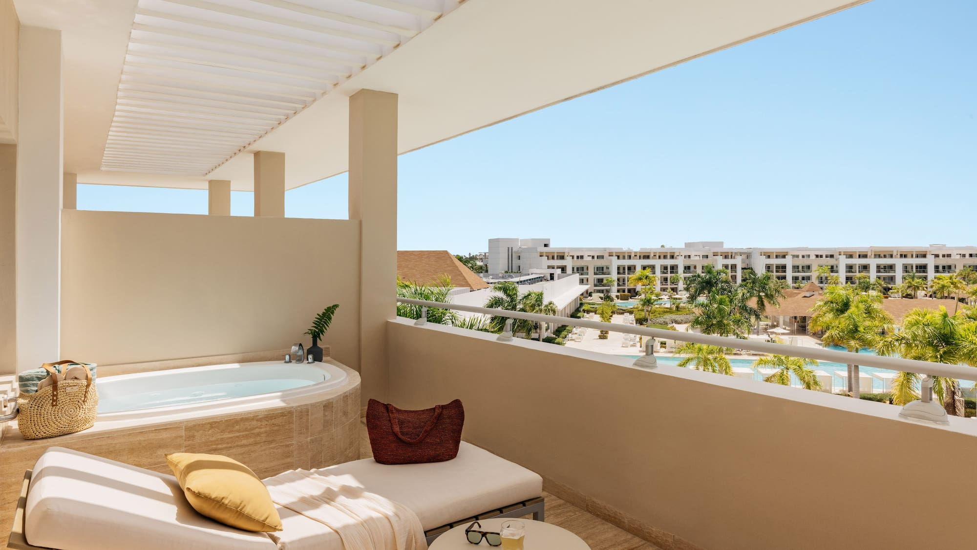 Luxury resort balcony with jacuzzi, lounge, and pool view.