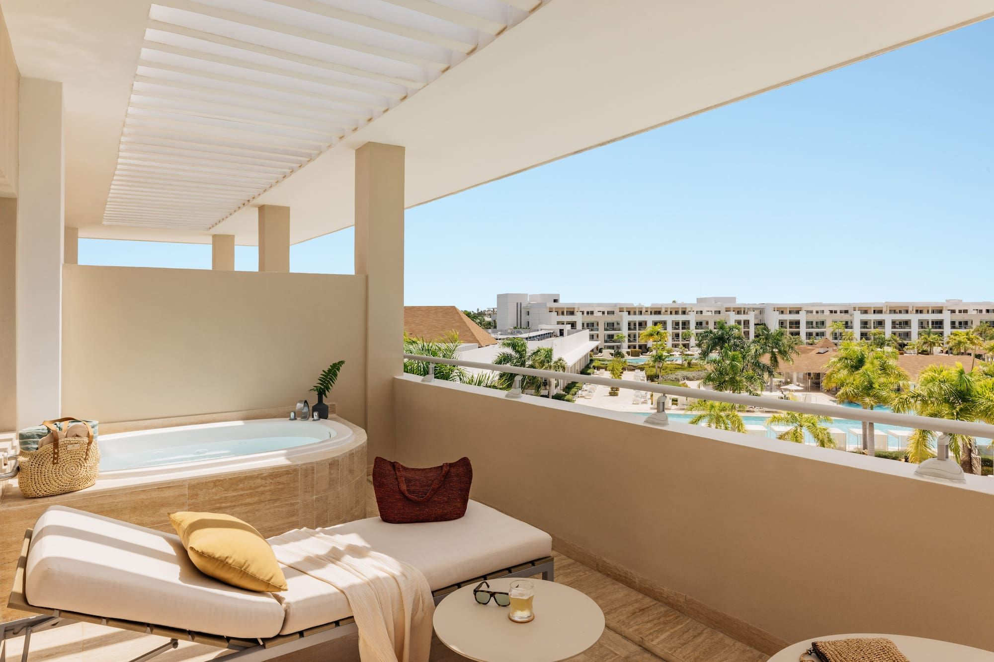 Luxury resort balcony with jacuzzi, lounge, and pool view.