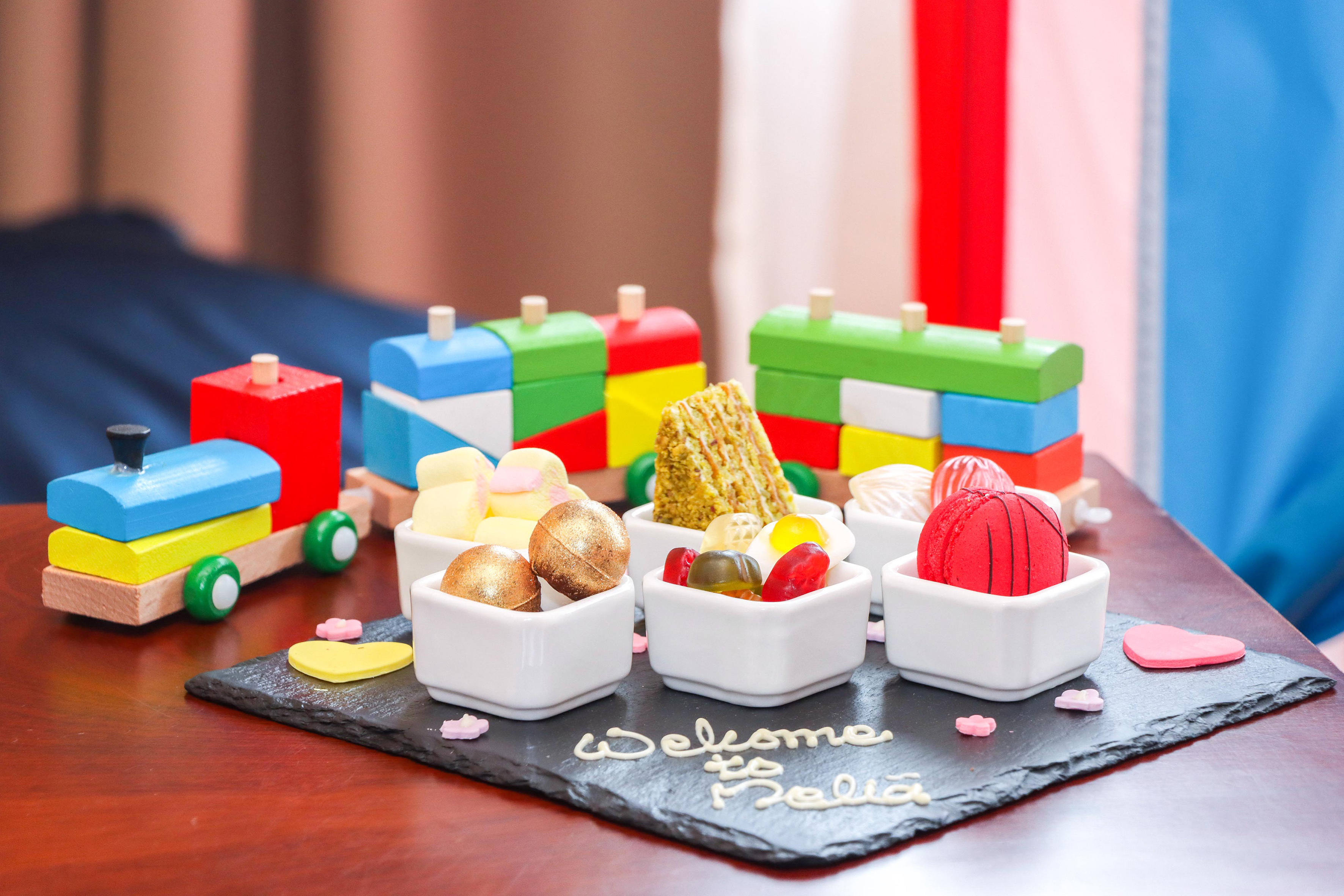 Colorful wooden toy trains, "Welcome to Delia" slate with mini desserts.