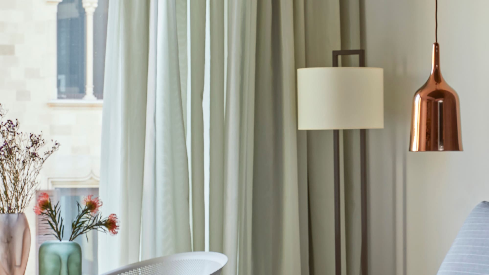 a bed with a lamp and vases of flowers