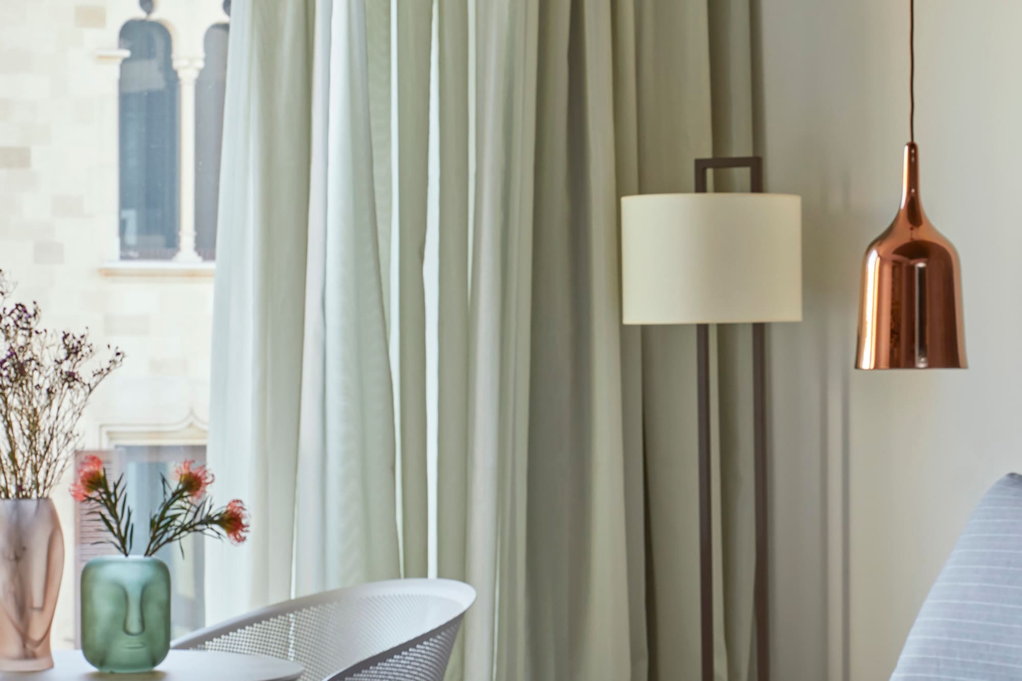 a bed with a lamp and vases of flowers