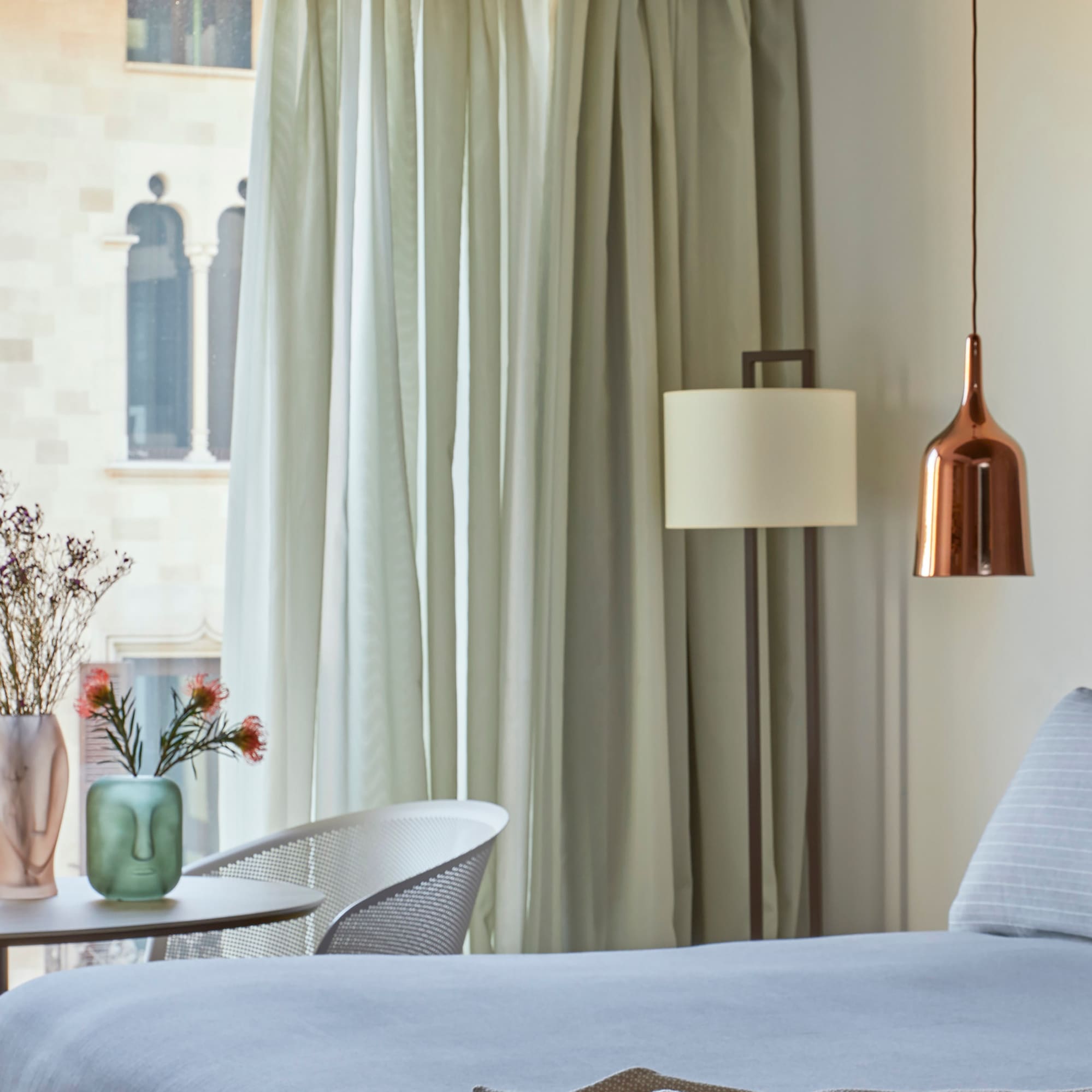 a bed with a lamp and vases of flowers