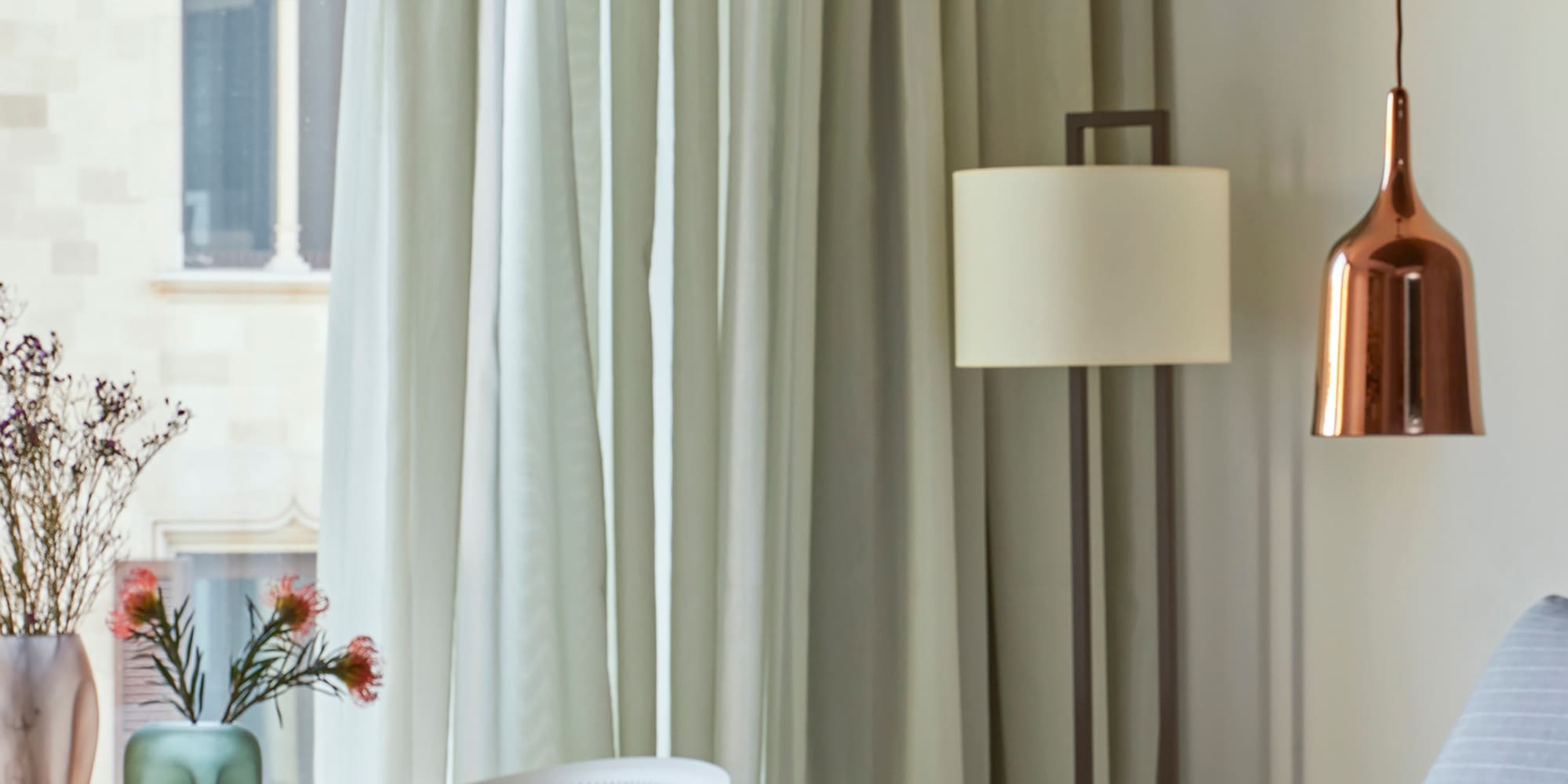 a bed with a lamp and vases of flowers