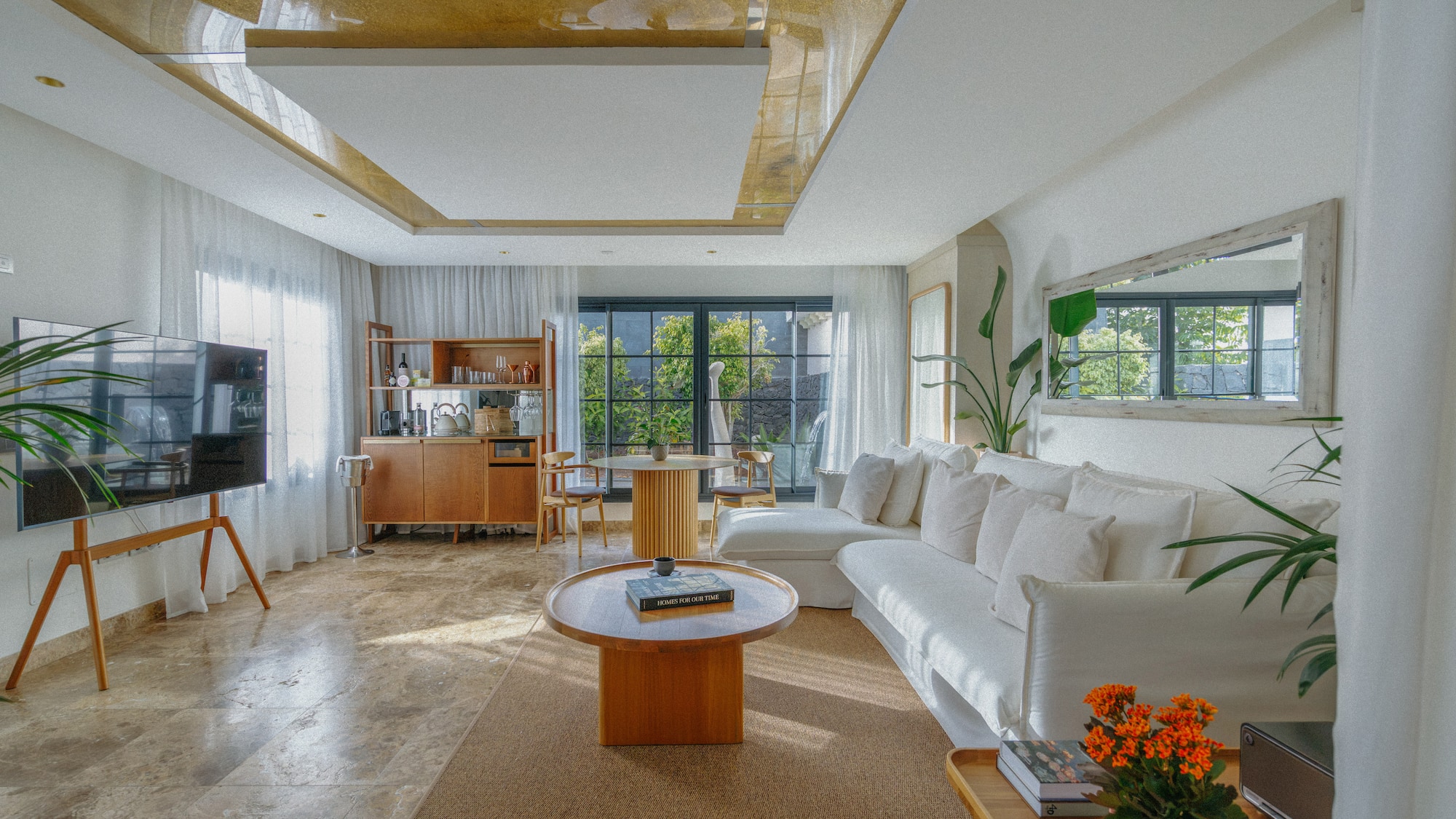 Bright modern living room with white sofa, wood furniture, and garden view.
