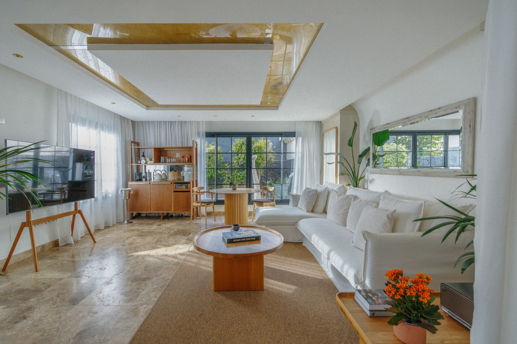 Bright modern living room with white sofa, wood furniture, and garden view.