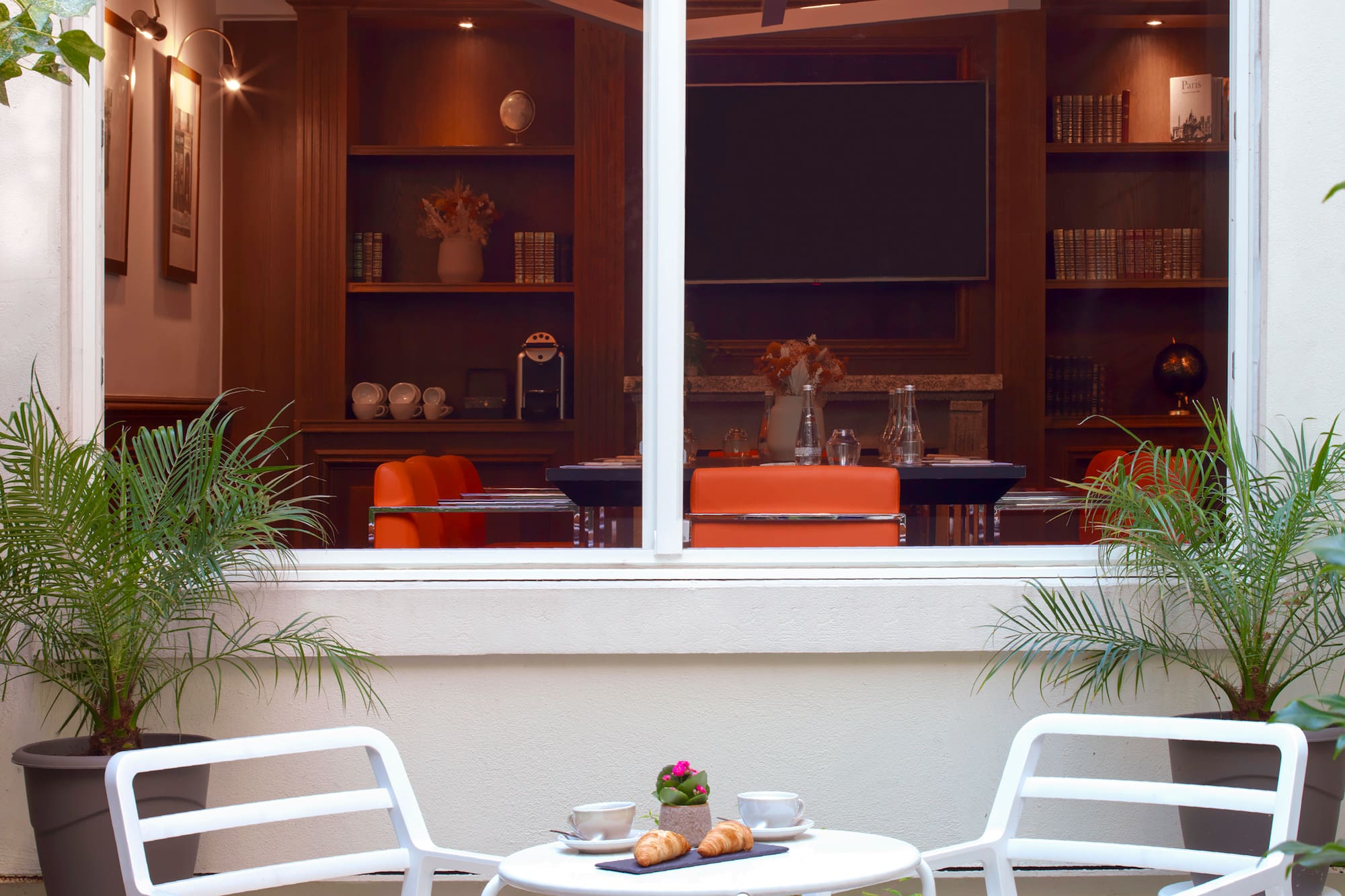 Hotel patio with coffee, croissants on white table, overlooking elegant lounge.