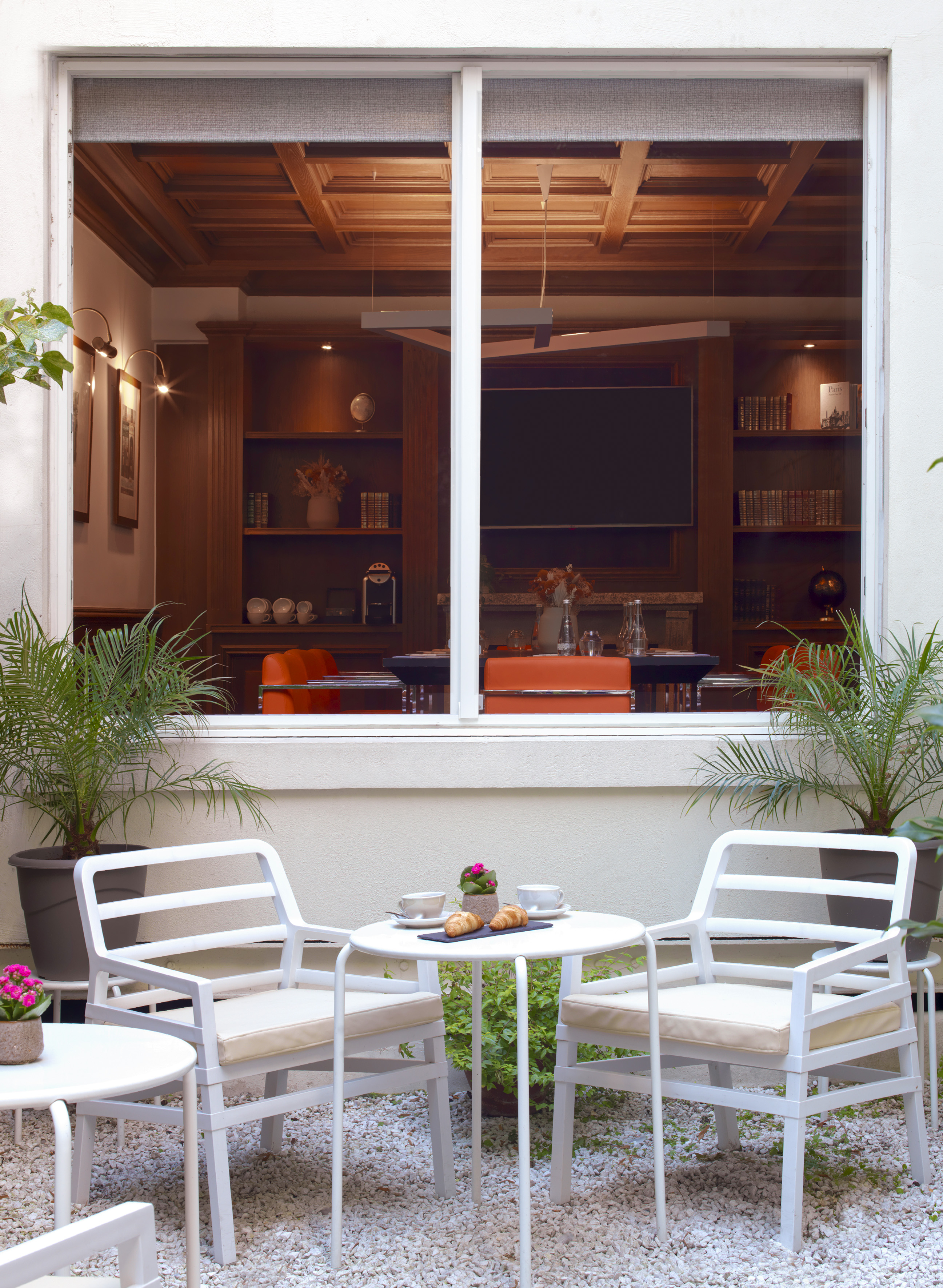 Hotel patio with coffee, croissants on white table, overlooking elegant lounge.