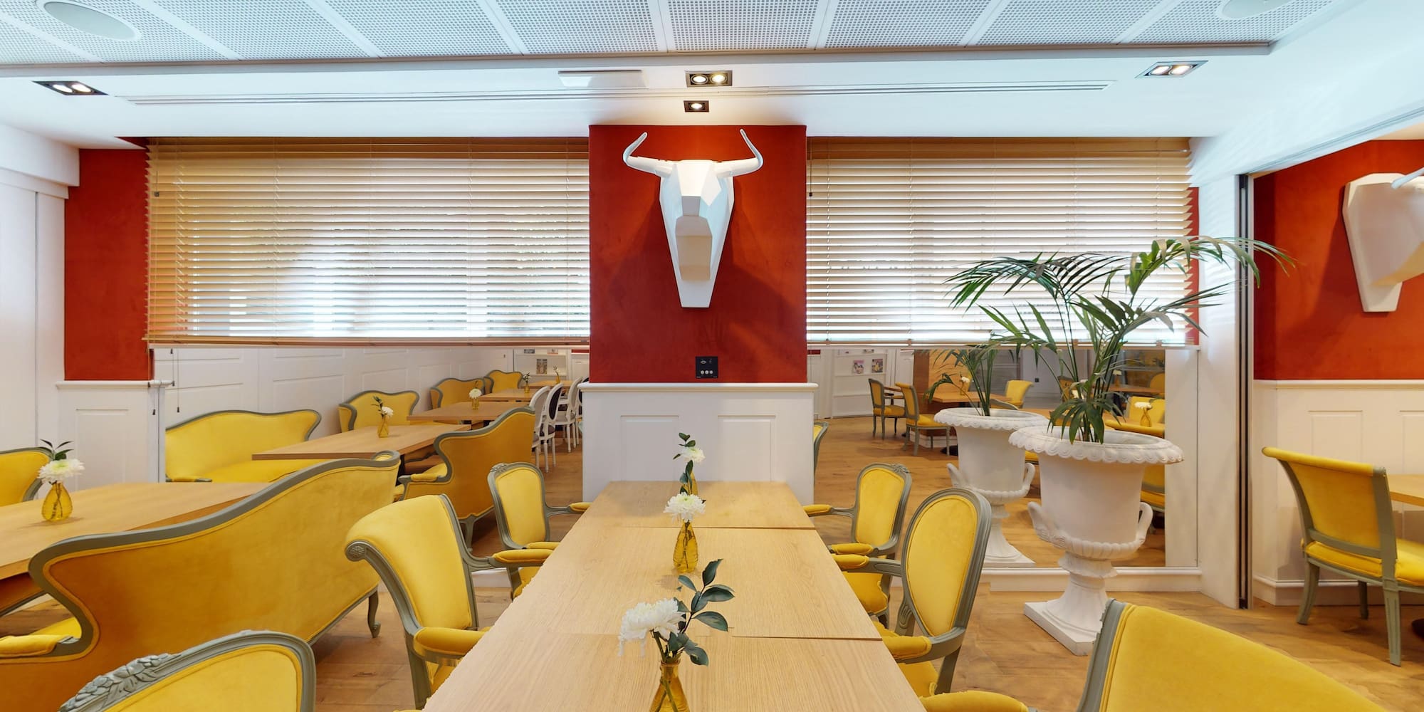 a room with yellow chairs and tables and a bull head sculpture