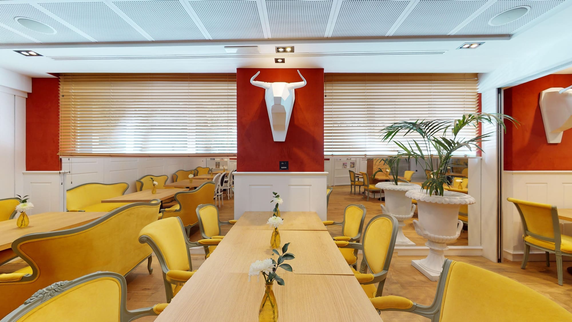 a room with yellow chairs and tables and a bull head sculpture