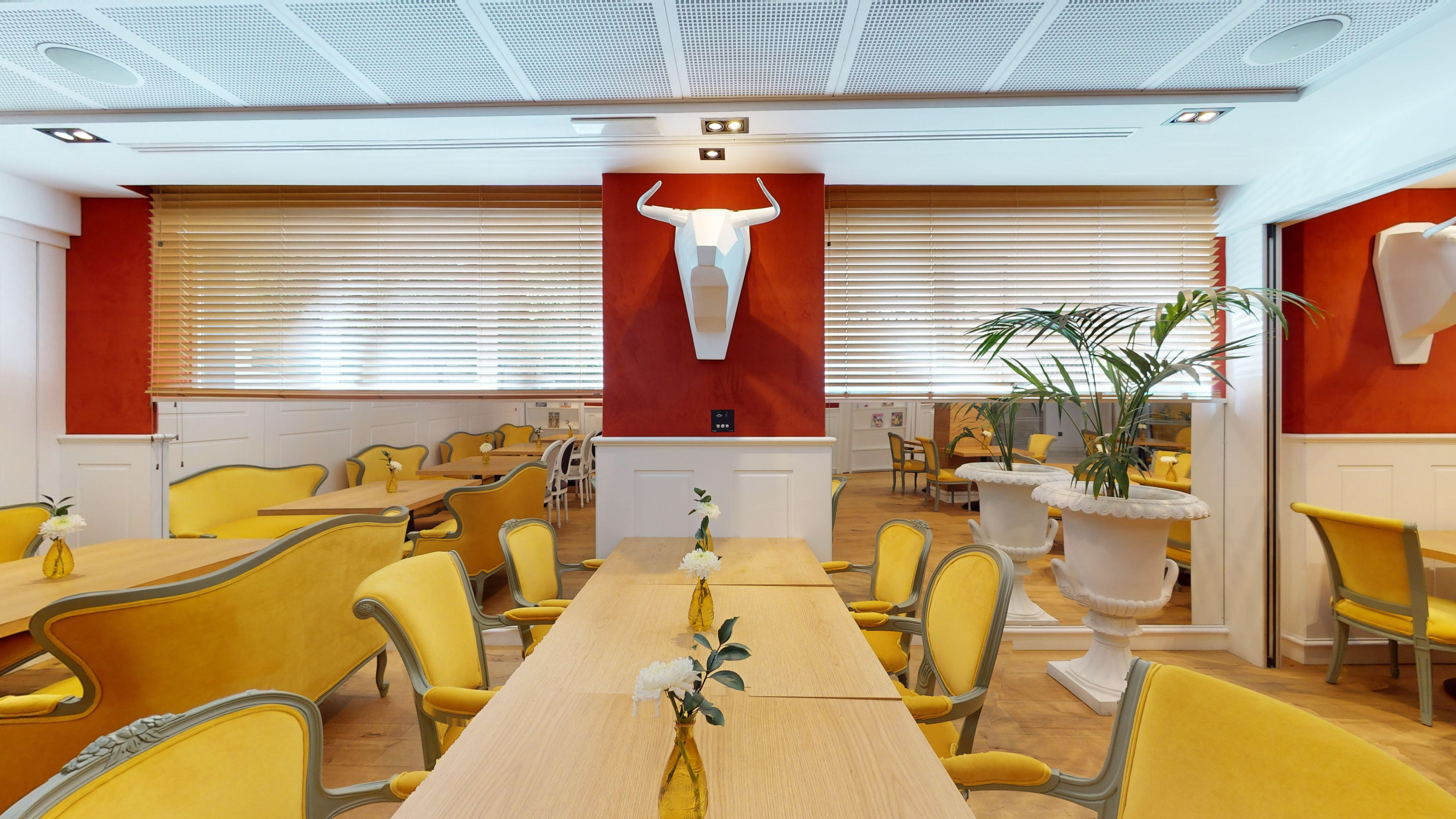 Yellow chairs and white bull head sculpture in a modern restaurant dining room.