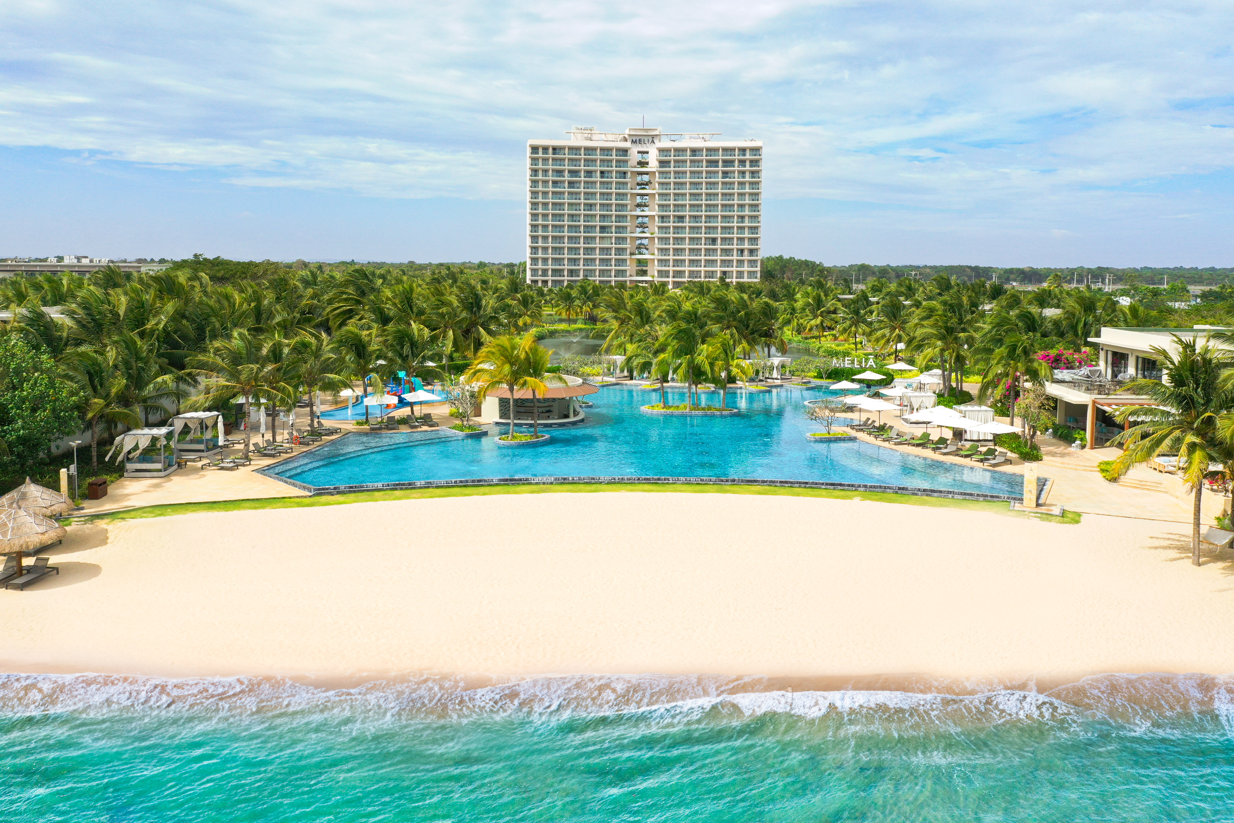 a pool with palm trees and a building in the background