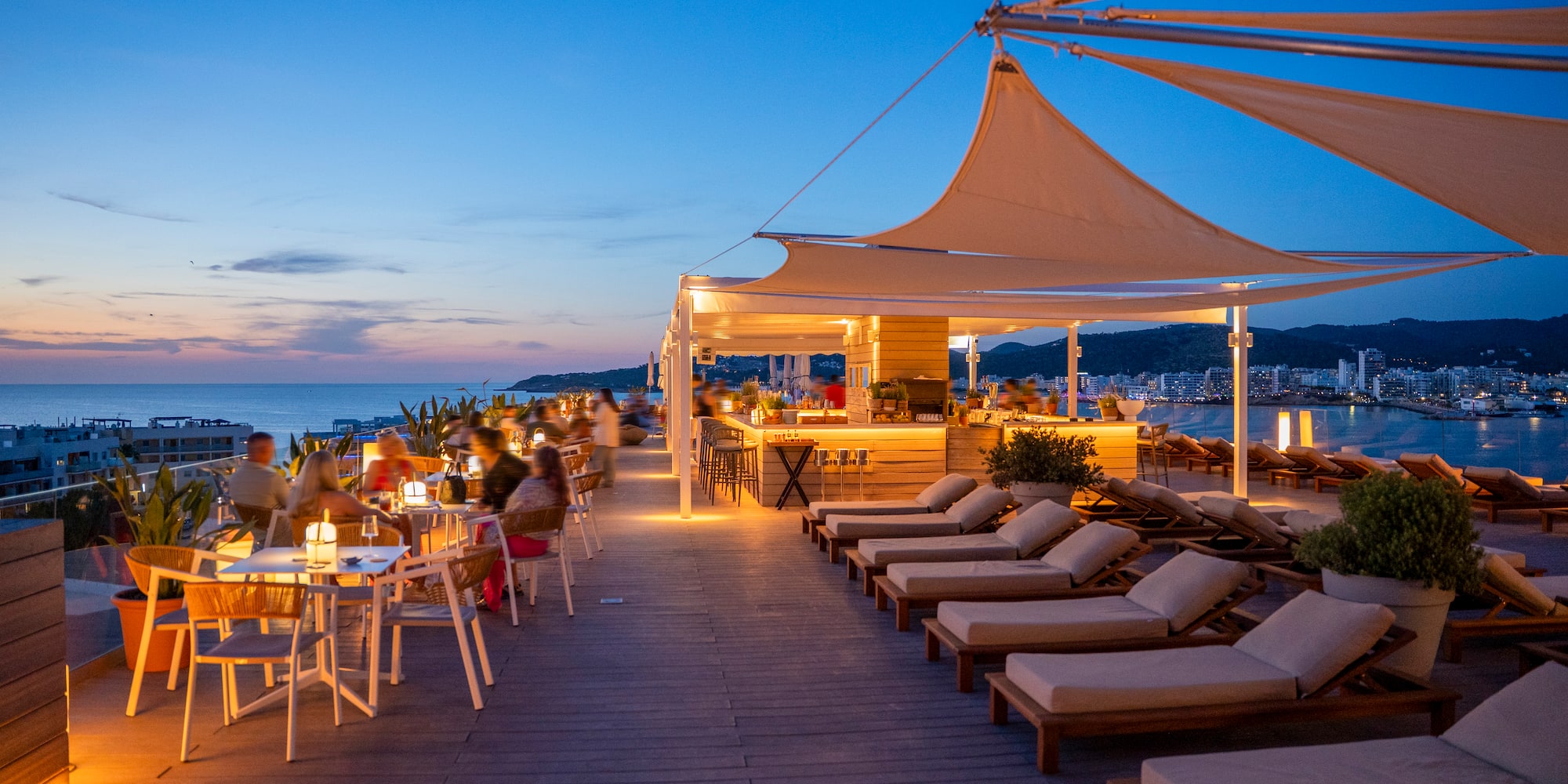 a group of people sitting at tables and chairs on a deck