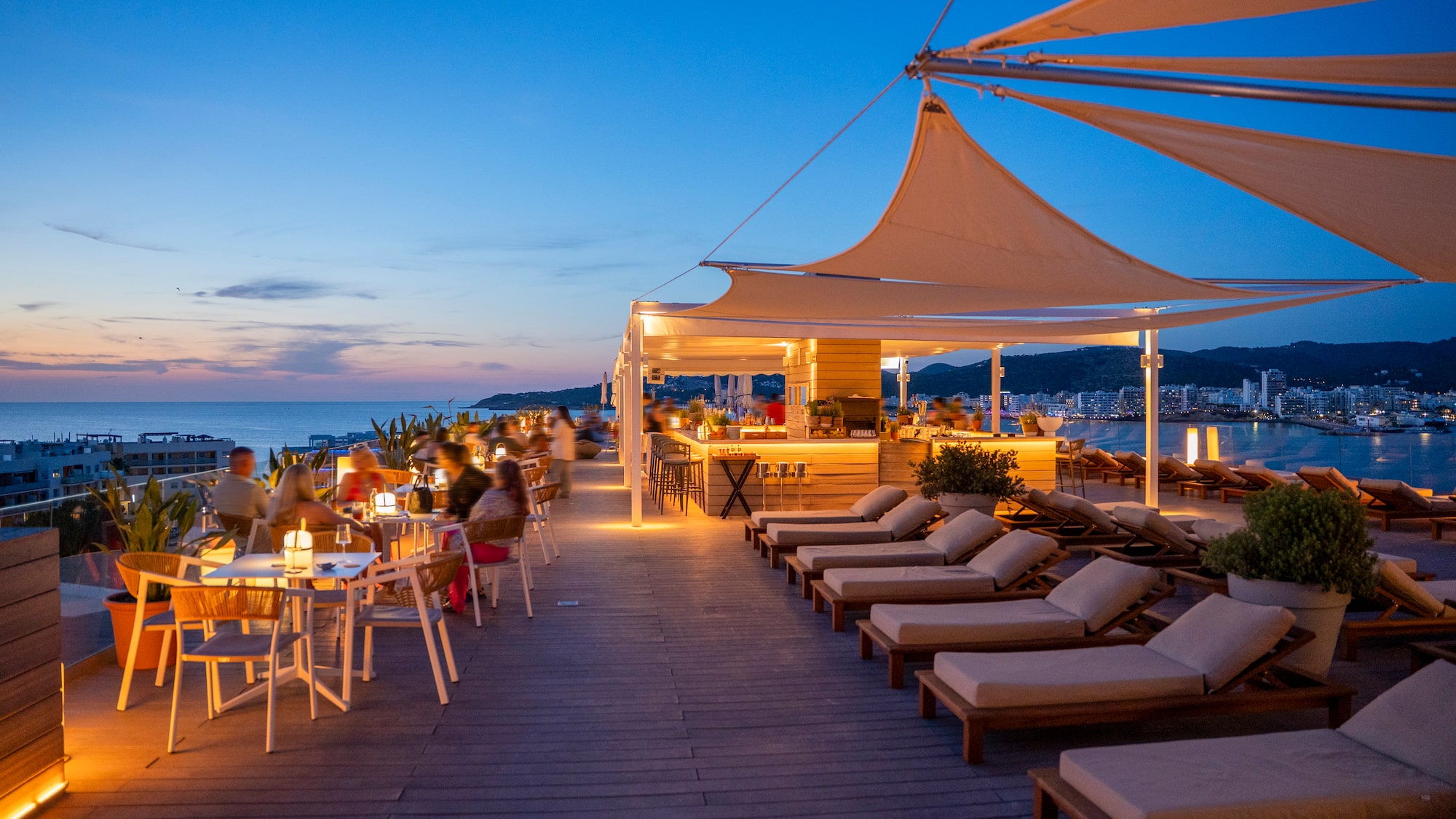 a group of people sitting at tables and chairs on a deck
