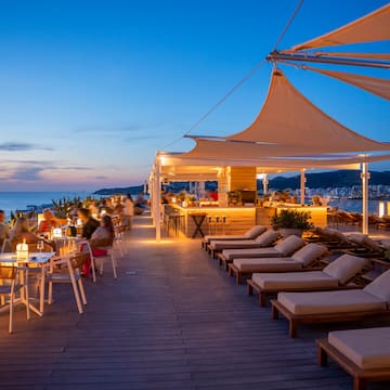 a group of people sitting at tables and chairs on a deck