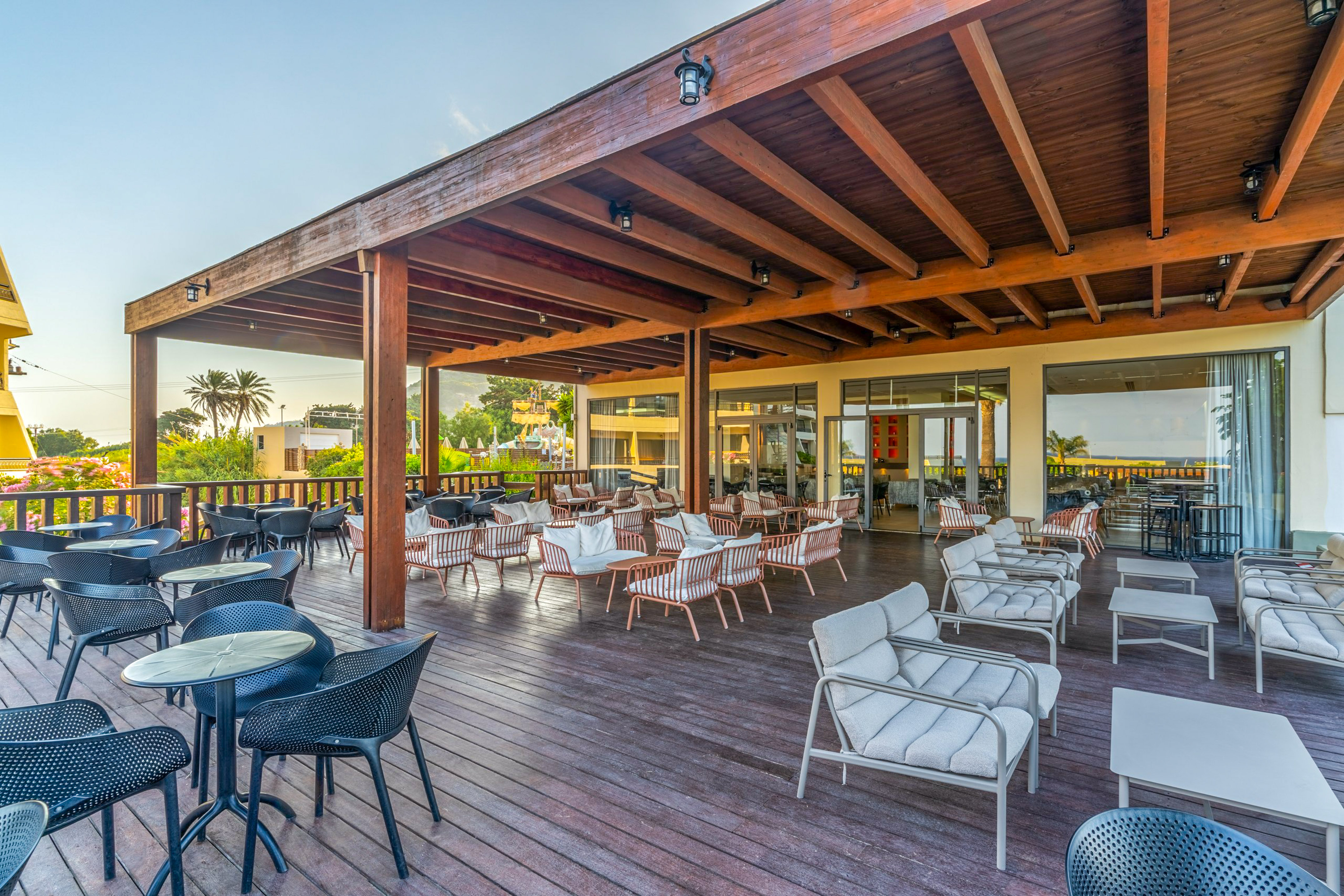 Spacious hotel patio with wooden deck, pergola, varied seating, and palm trees.