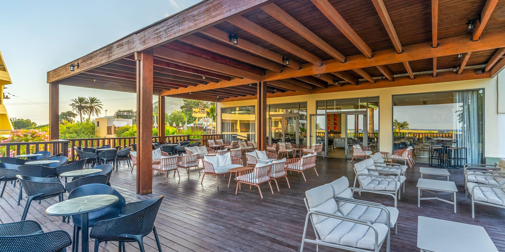 Spacious hotel patio with wooden deck, pergola, varied seating, and palm trees.