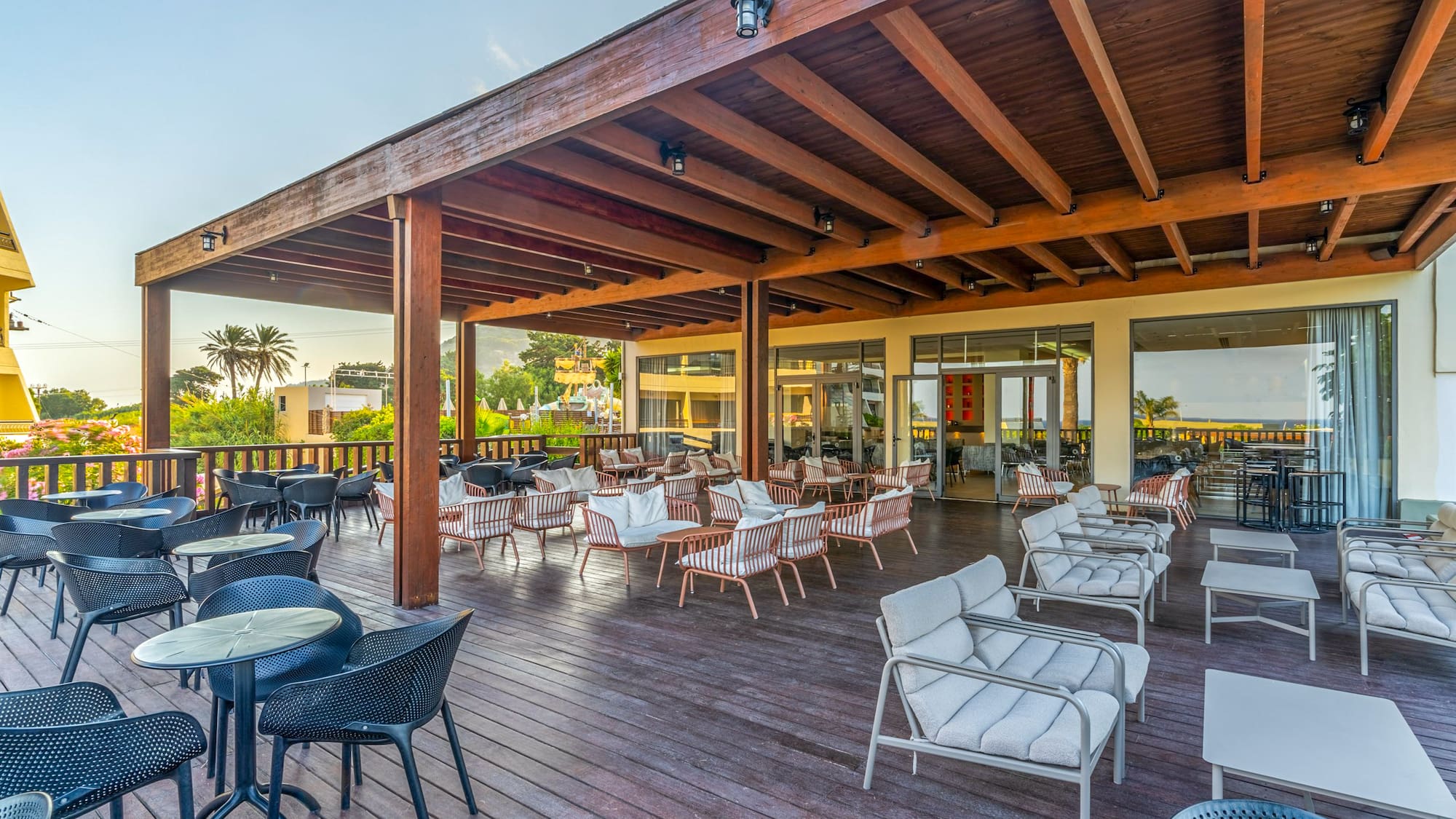Spacious hotel patio with wooden deck, pergola, varied seating, and palm trees.